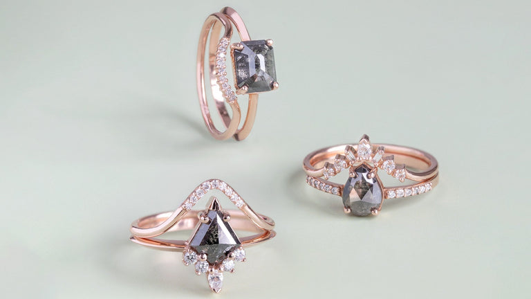 three black diamond engagement rings in 14K rose gold featuring different engagement ring band styles on sage green background