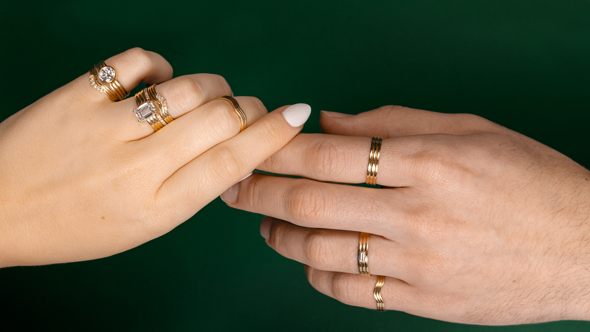 Model's holding hands wearing 18K Yellow Gold Rings with Emerald Green Background