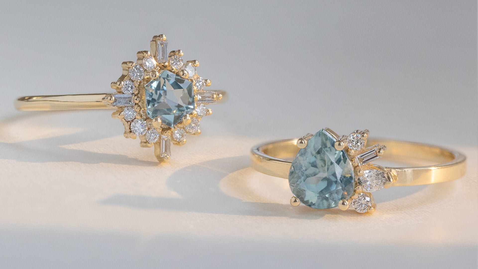two yellow gold blue sapphire engagement rings in ray of light