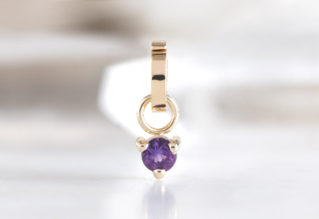 10k Yellow Gold Amethyst Birthstone Charm on White Marble Tile