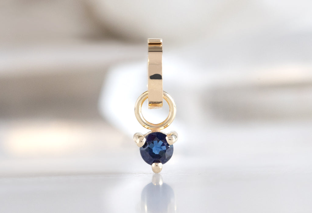10k Yellow Gold Sapphire Birthstone Charm on White Marble Tile