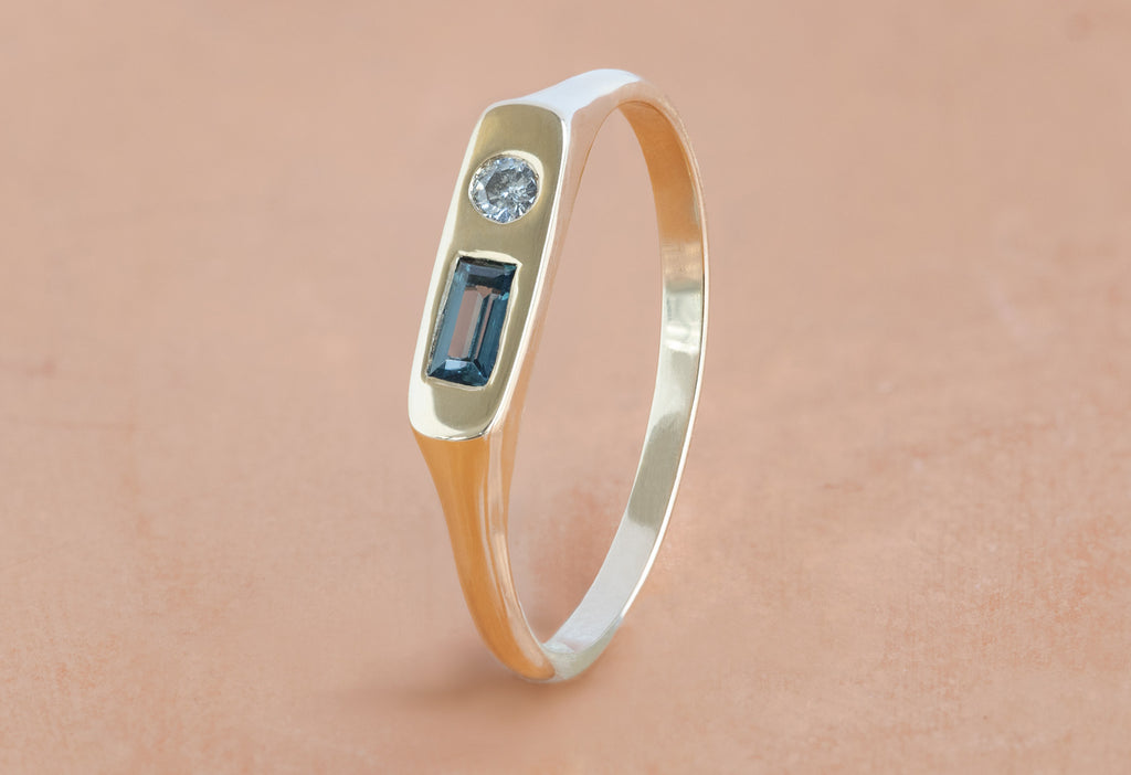 Asymmetrical Sapphire + Diamond Signet Ring Standing on Orange Background