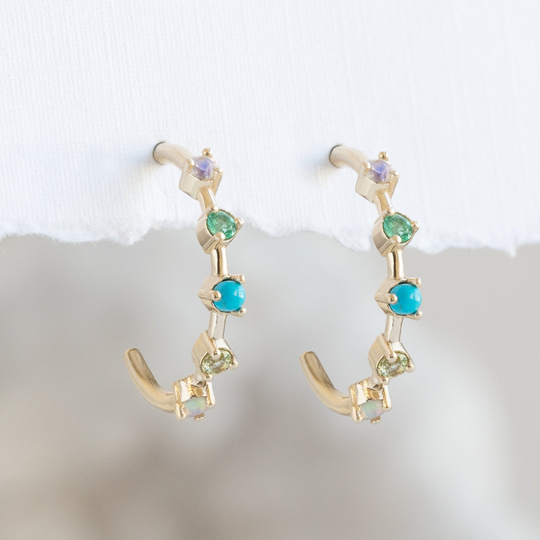 The Custom Multi-Birthstone Hoops 5 Stone Option Hanging on White Textured Paper
