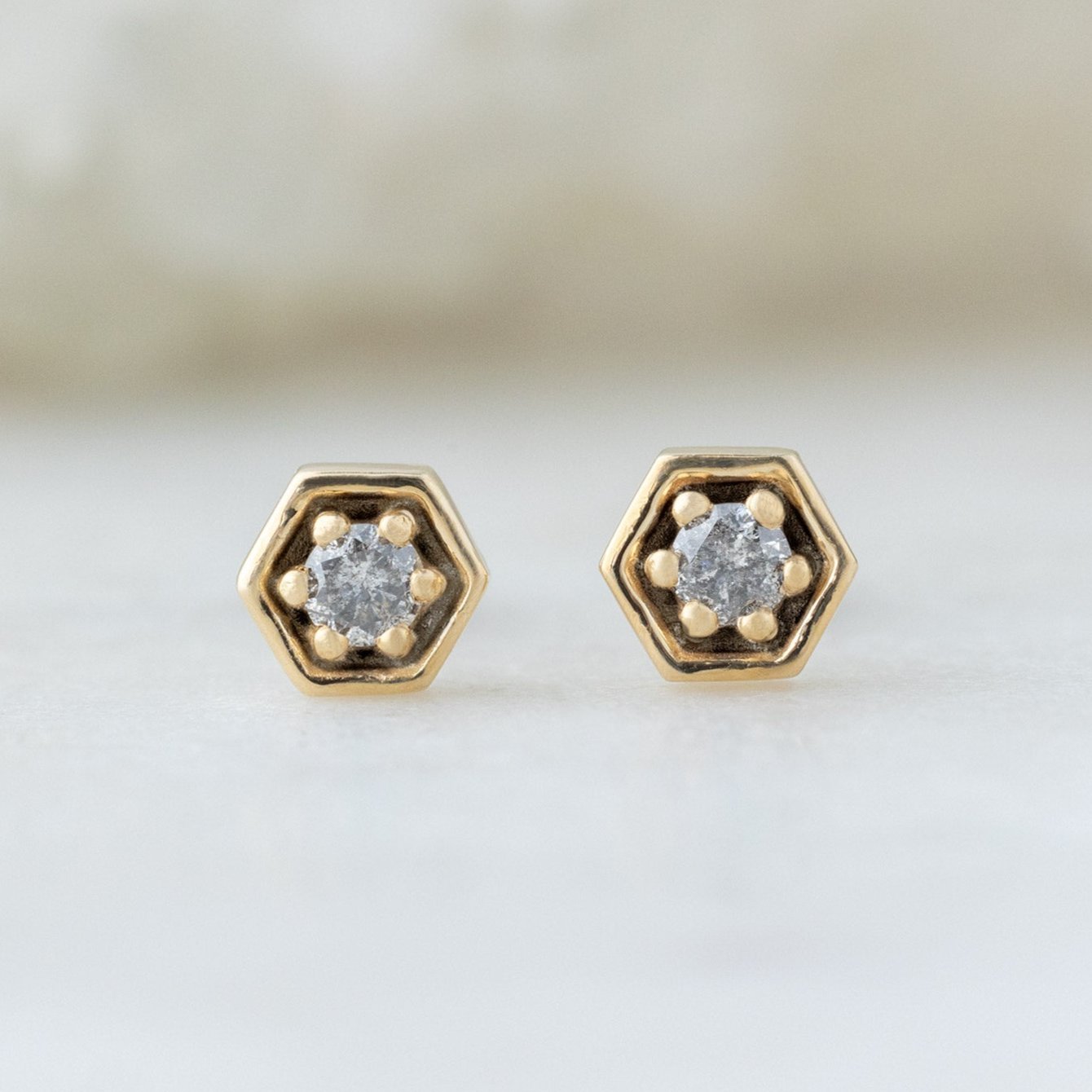 The Galaxy Salt and Pepper Diamond Hexagon Stud Earrings in 14K Yellow Gold on White Marble
