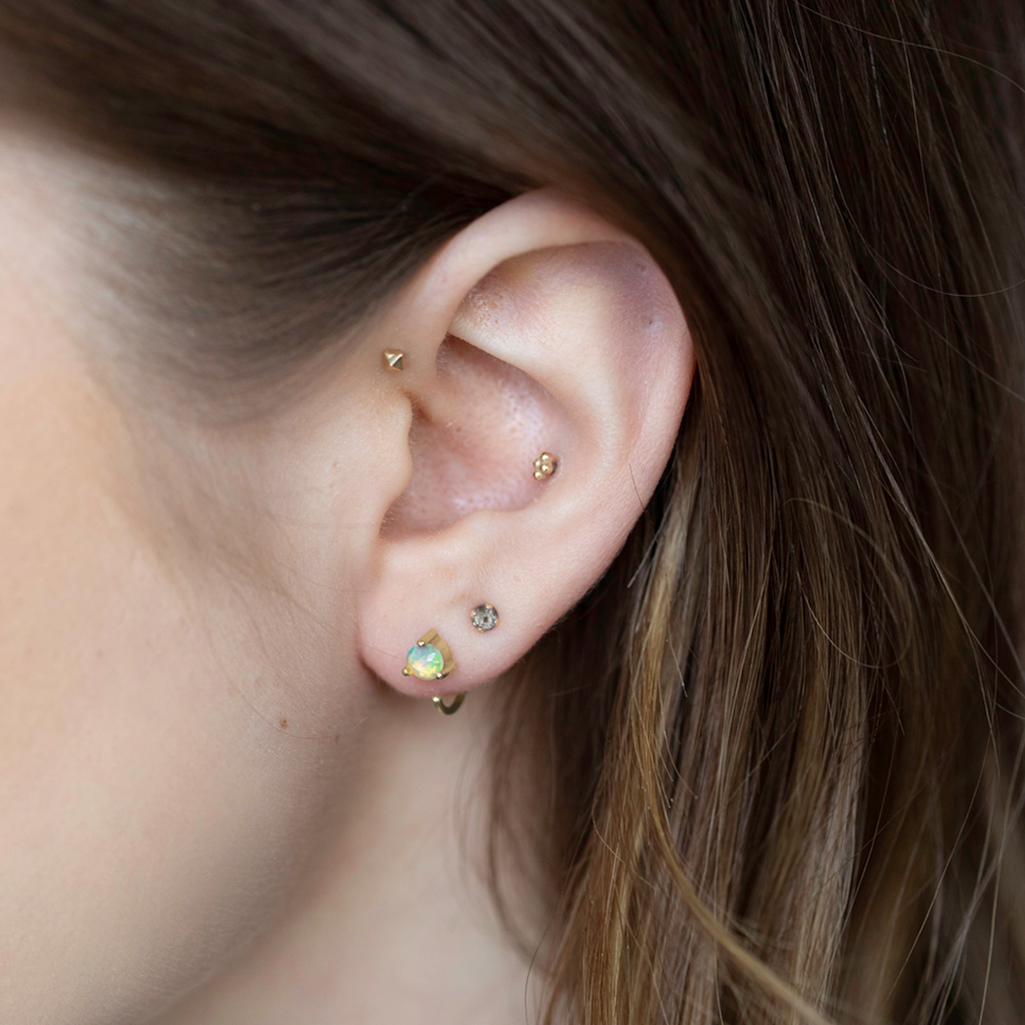 The Opal Huggie Stud Earrings in 14K Yellow Gold Stacked on Model