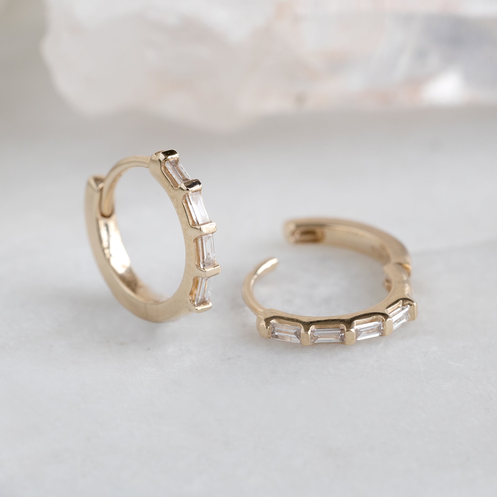 The Baguette White Diamond Huggie Hoops in 14K Yellow Gold on White Marble