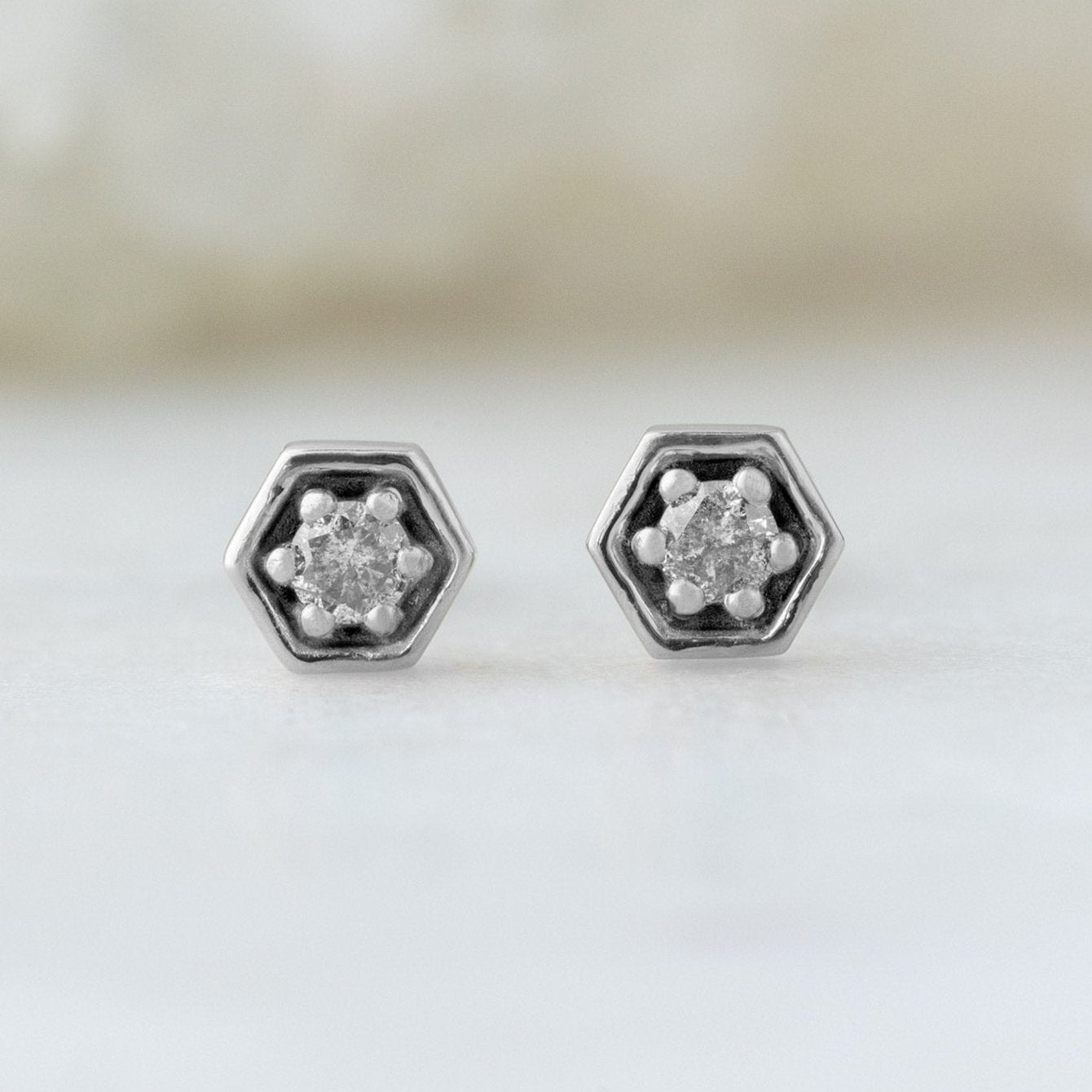 The Galaxy Salt and Pepper Diamond Hexagon Stud Earrings in 14K White Gold on White Marble