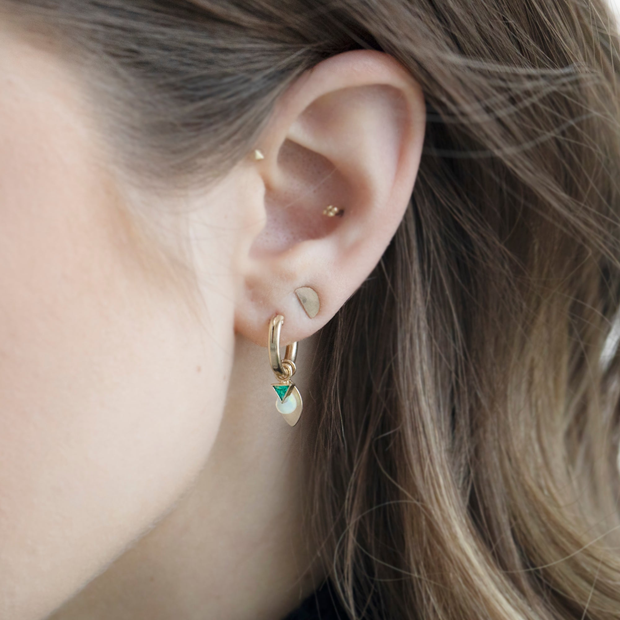 Custom Charm Hoop Earrings | Yellow Gold Filled displayed on model's ear with additional stud earrings.