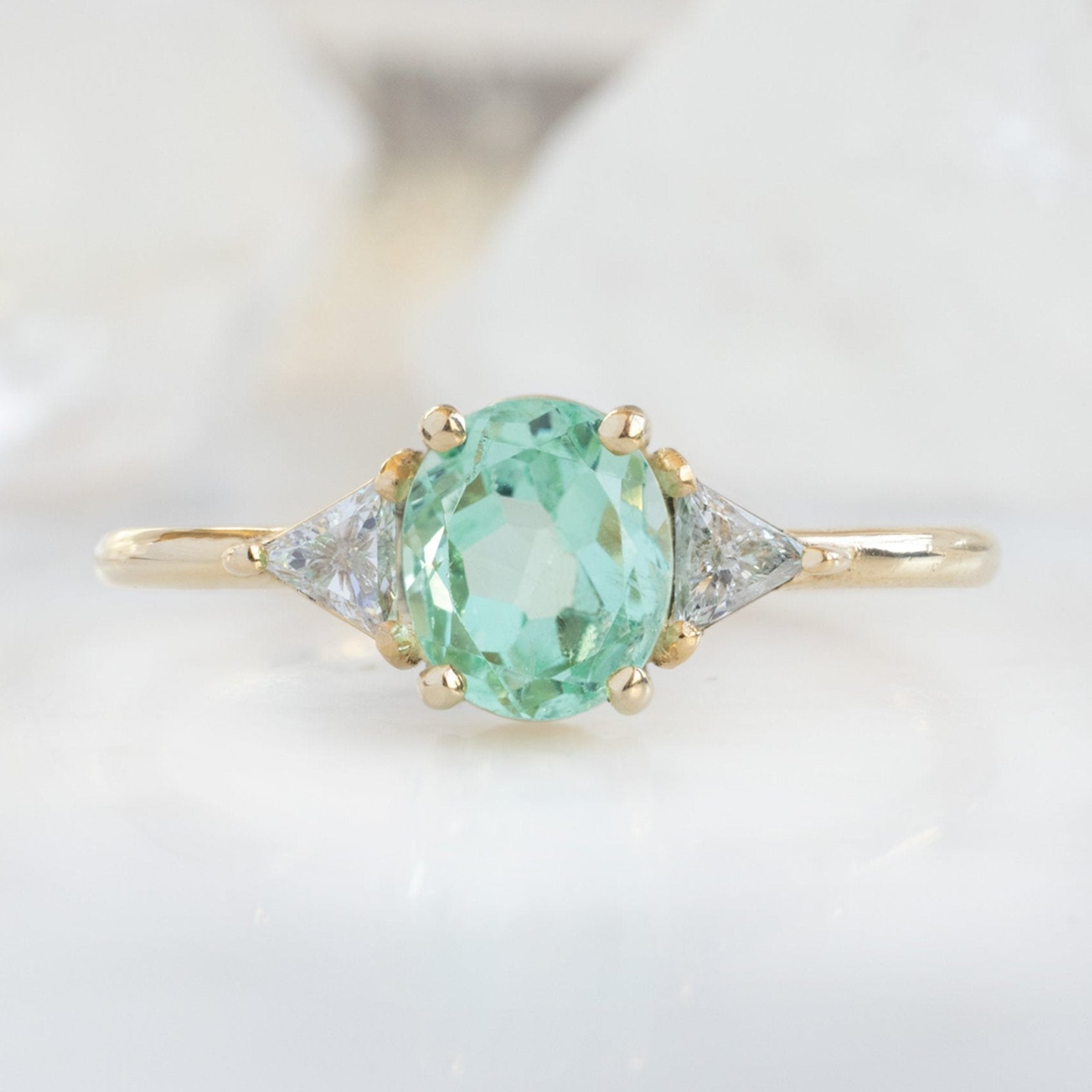 The Jade Ring with a 0.89ct Oval Emerald in 14K Yellow Gold on White Marble