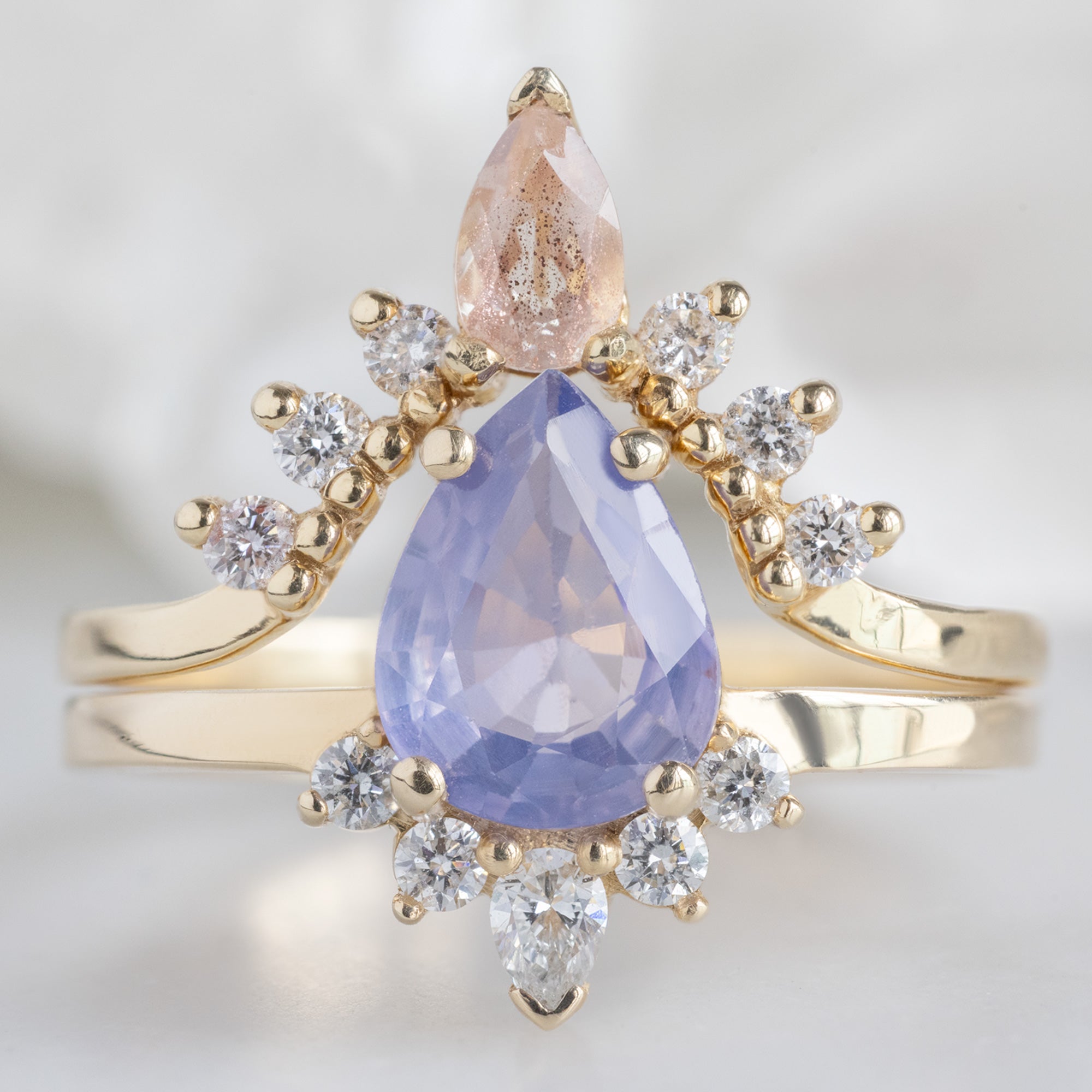The Aster Ring with a 1.23ct Pear Cut Lavender Sapphire in 14K Yellow Gold Stacked with the Sunstone and White Diamond Sunburst Stacking Band