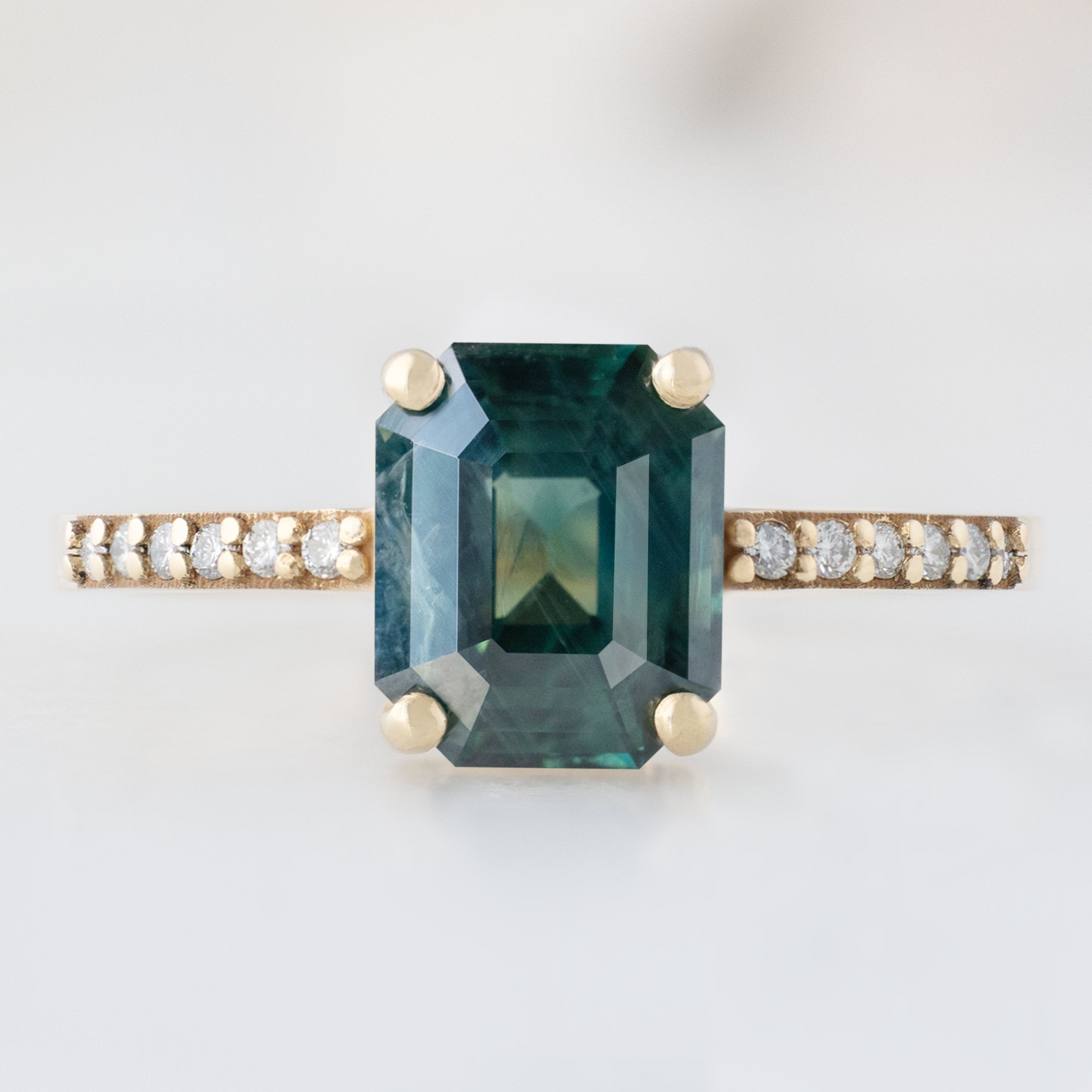 The Willow Ring with a 2.00ct Emerald Cut Teal Sapphire in 14K Yellow Gold on white background