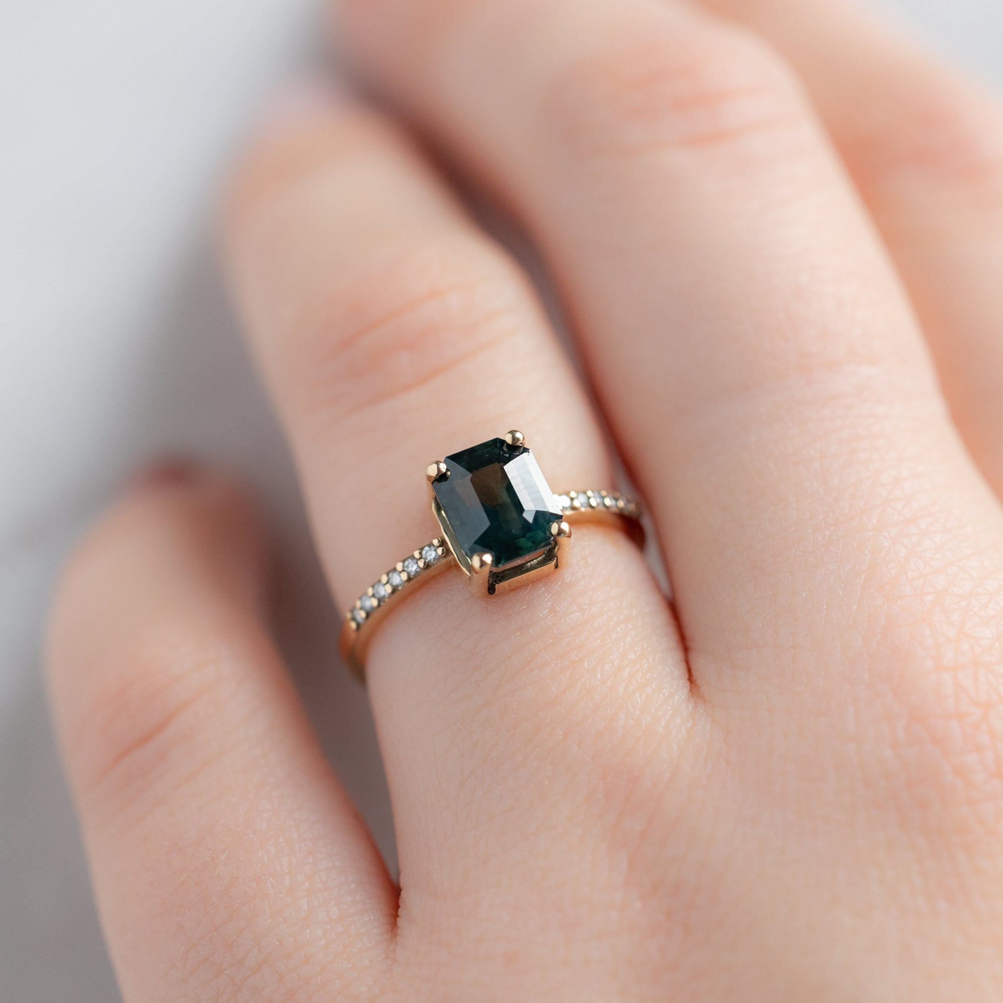 The Willow Ring with a 2.00ct Emerald Cut Teal Sapphire in 14K Yellow Gold on white background on Model