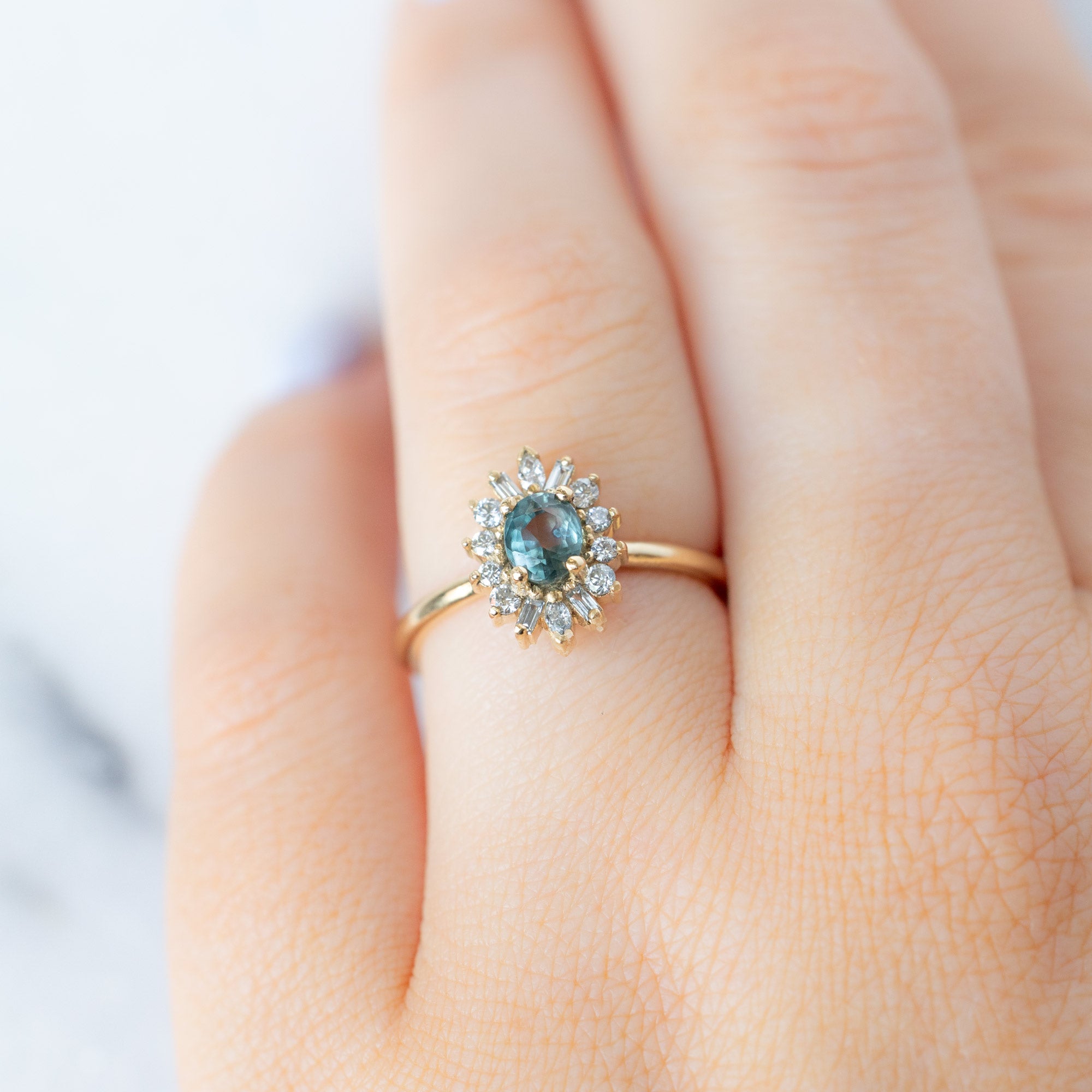 The Camellia Ring with a 0.81ct Oval Blue Montana Sapphire in 14K Yellow Gold on Model