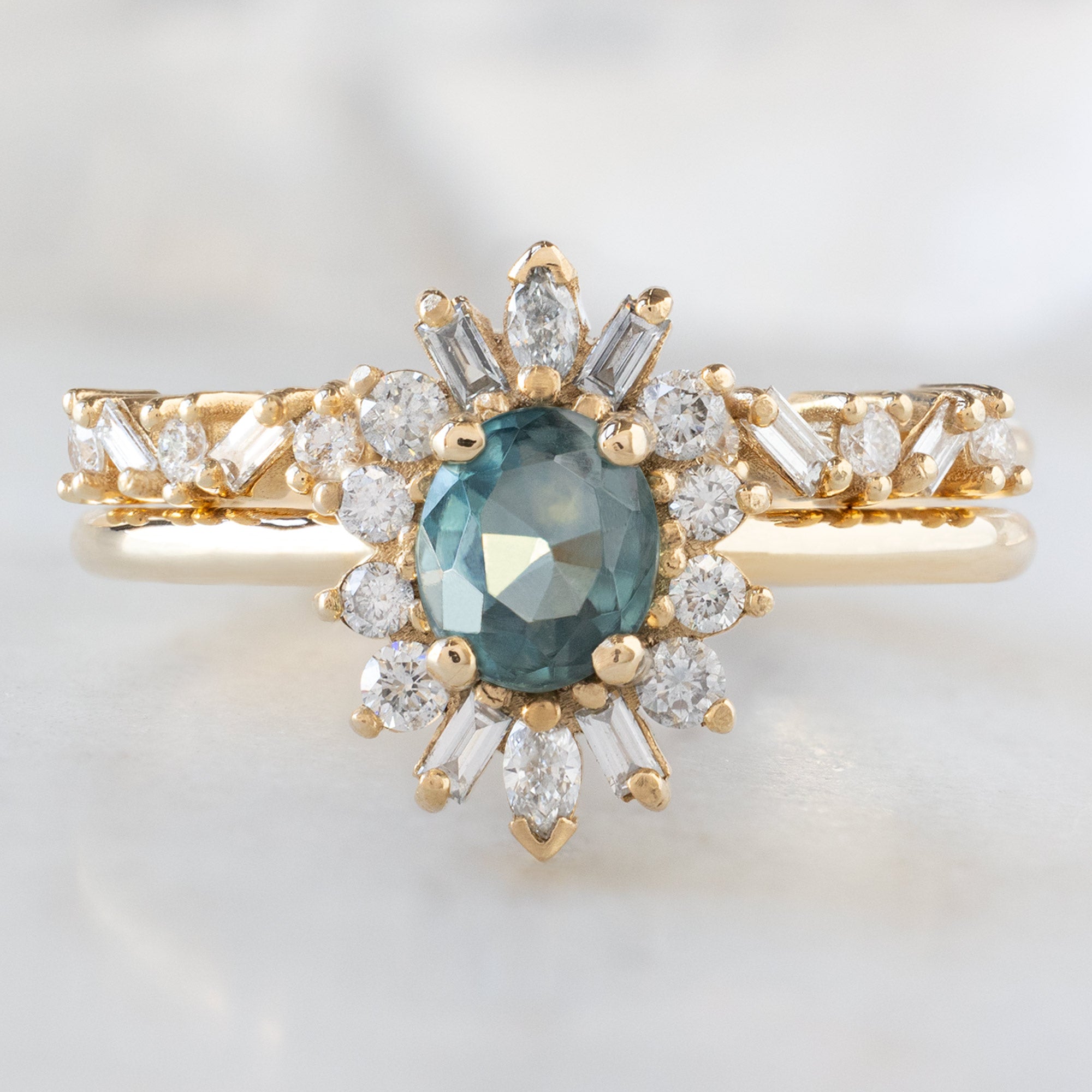 The Camellia Ring with a 0.81ct Oval Blue Montana Sapphire in 14K Yellow Gold Stacked with the Confetti Baguette Stacking Ring