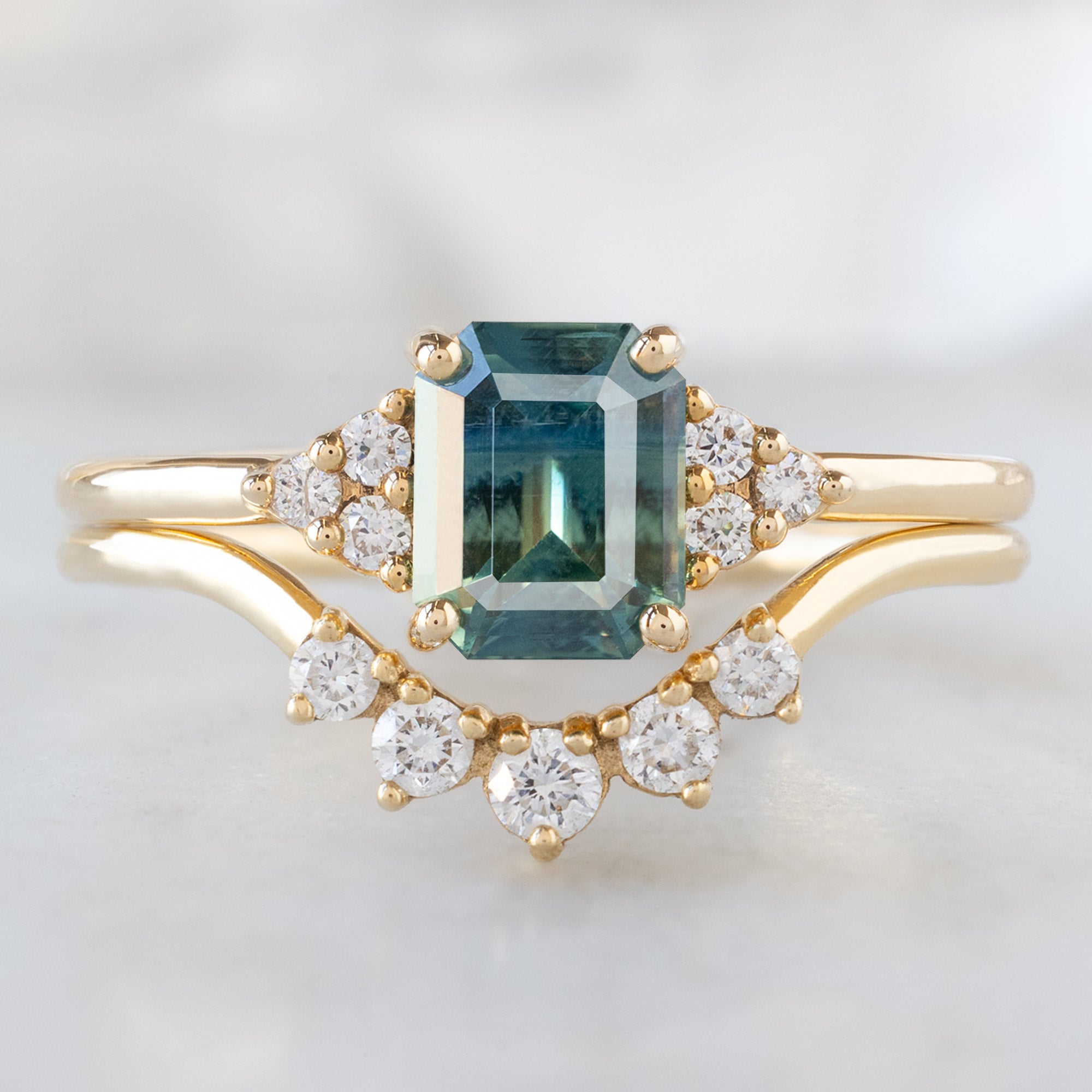 The Ivy Ring with a 1.06ct Emerald Cut Teal Sapphire in 14K Yellow Gold Stacked with the Round White Diamond Sunburst Stacking Band