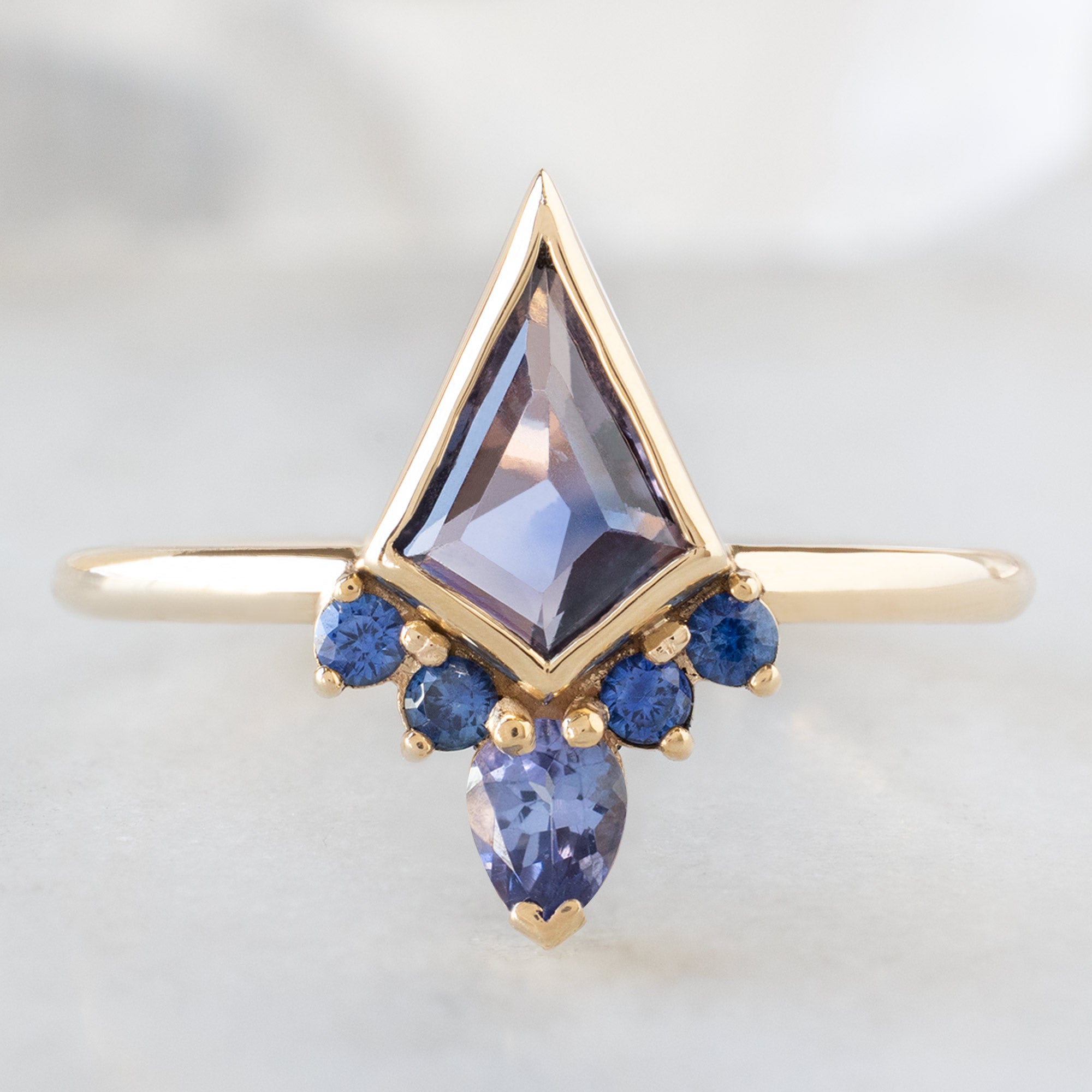 The Watercolor Aster Ring with a 0.83ct Violet Kite Sapphire in 14K Yellow Gold on White Marble