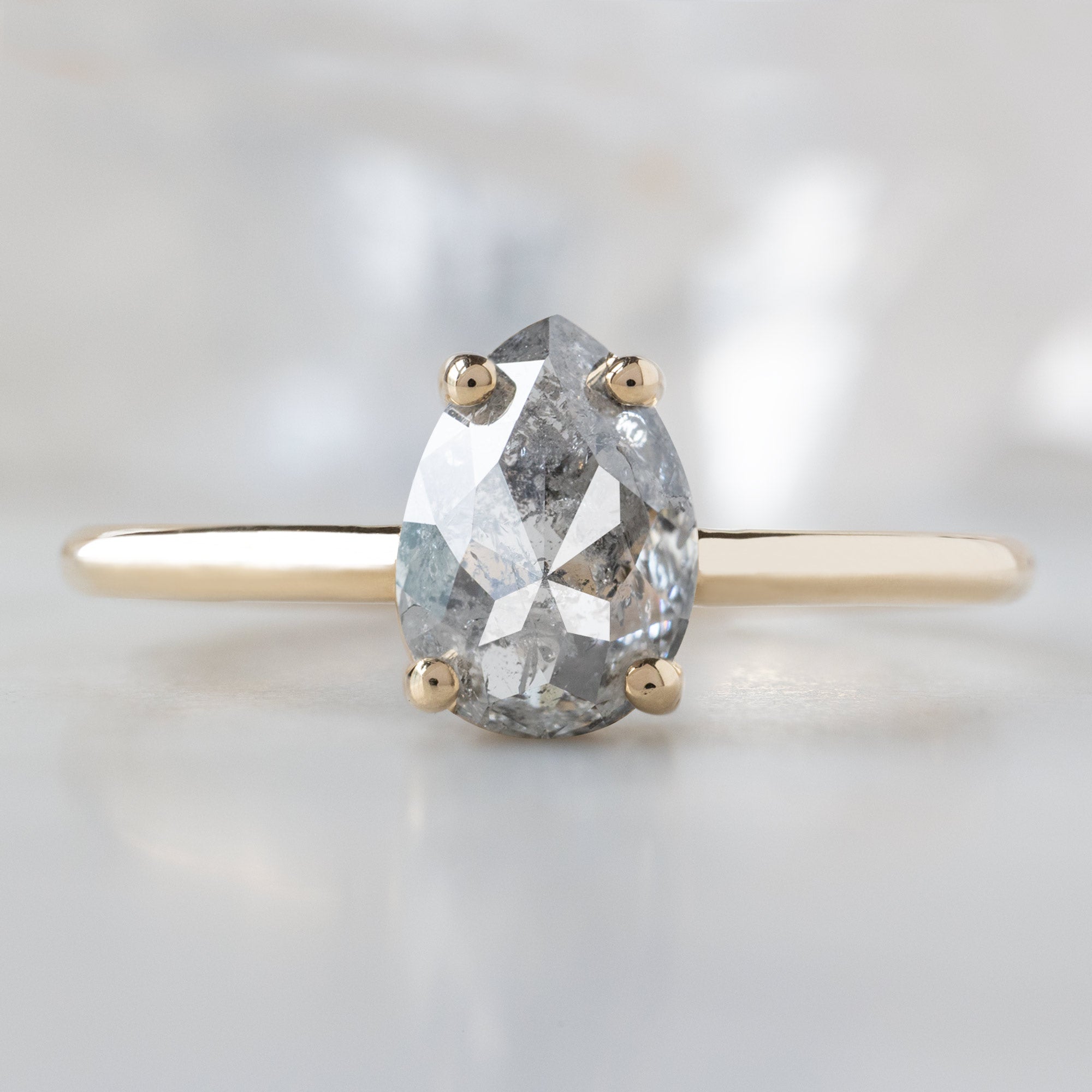The Bryn Ring with a 1.10ct Pear Salt and Pepper Diamond in 14K Yellow Gold on White Marble