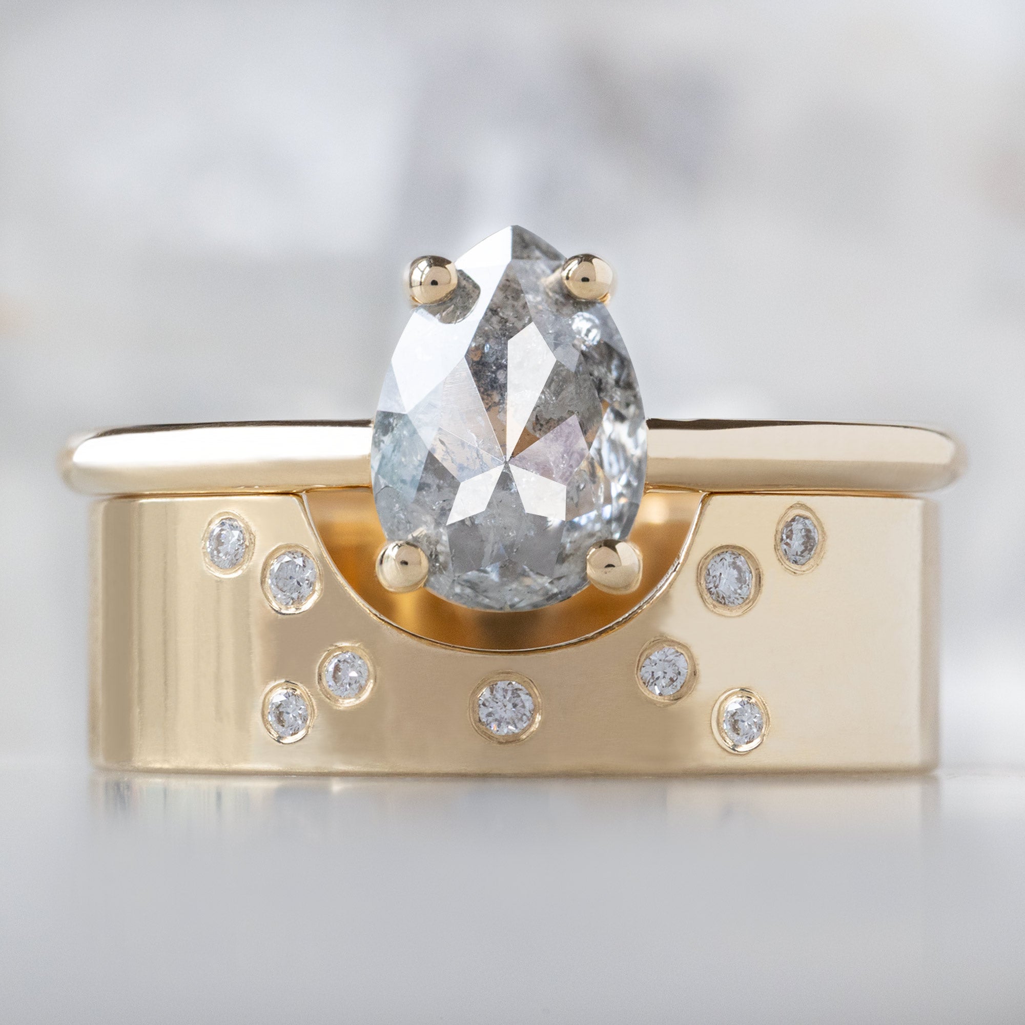 The Bryn Ring with a 1.10ct Pear Salt and Pepper Diamond in 14K Yellow Gold Stacked with the Constellation Arc Cut-Out Stacking Band