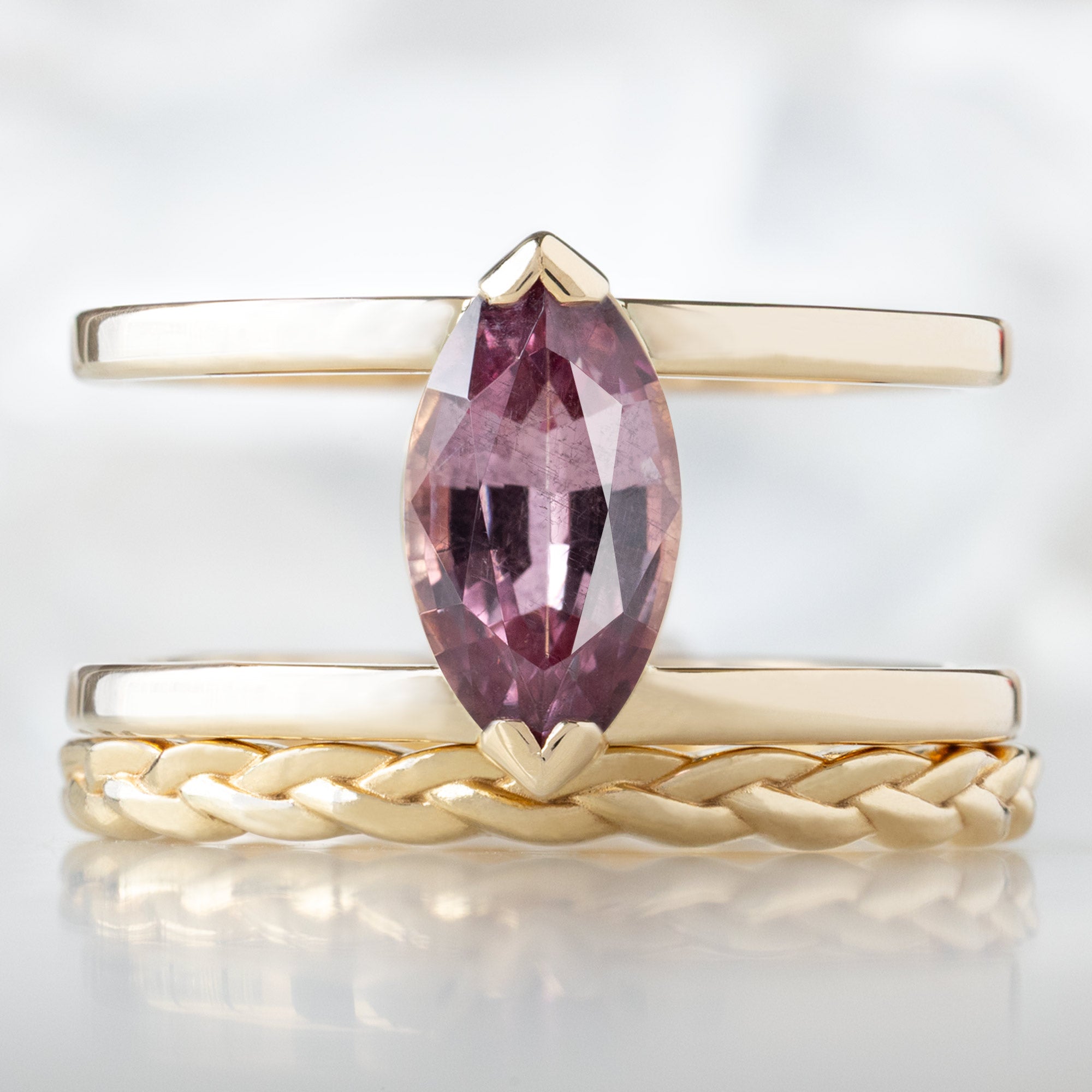 The Poppy Ring with a 1.38ct Marquise Mauve Garnet in 14K Yellow Gold Stacked with the Braided Stacking Band