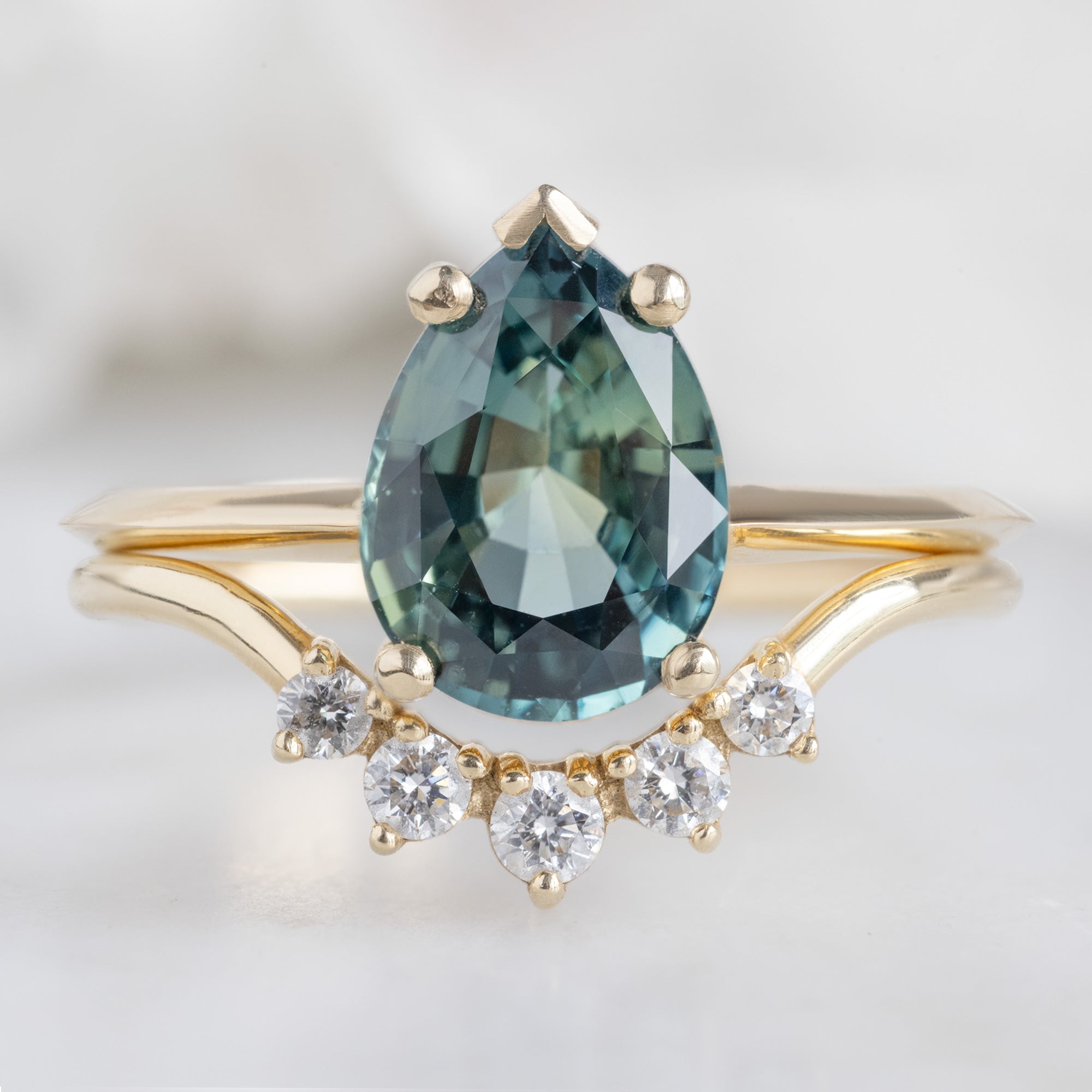 The Sage Ring with a 2.04ct Pear Teal Sapphire in 14 Yellow Gold Stacked with the Round White Diamond Sunburst Stacking Band