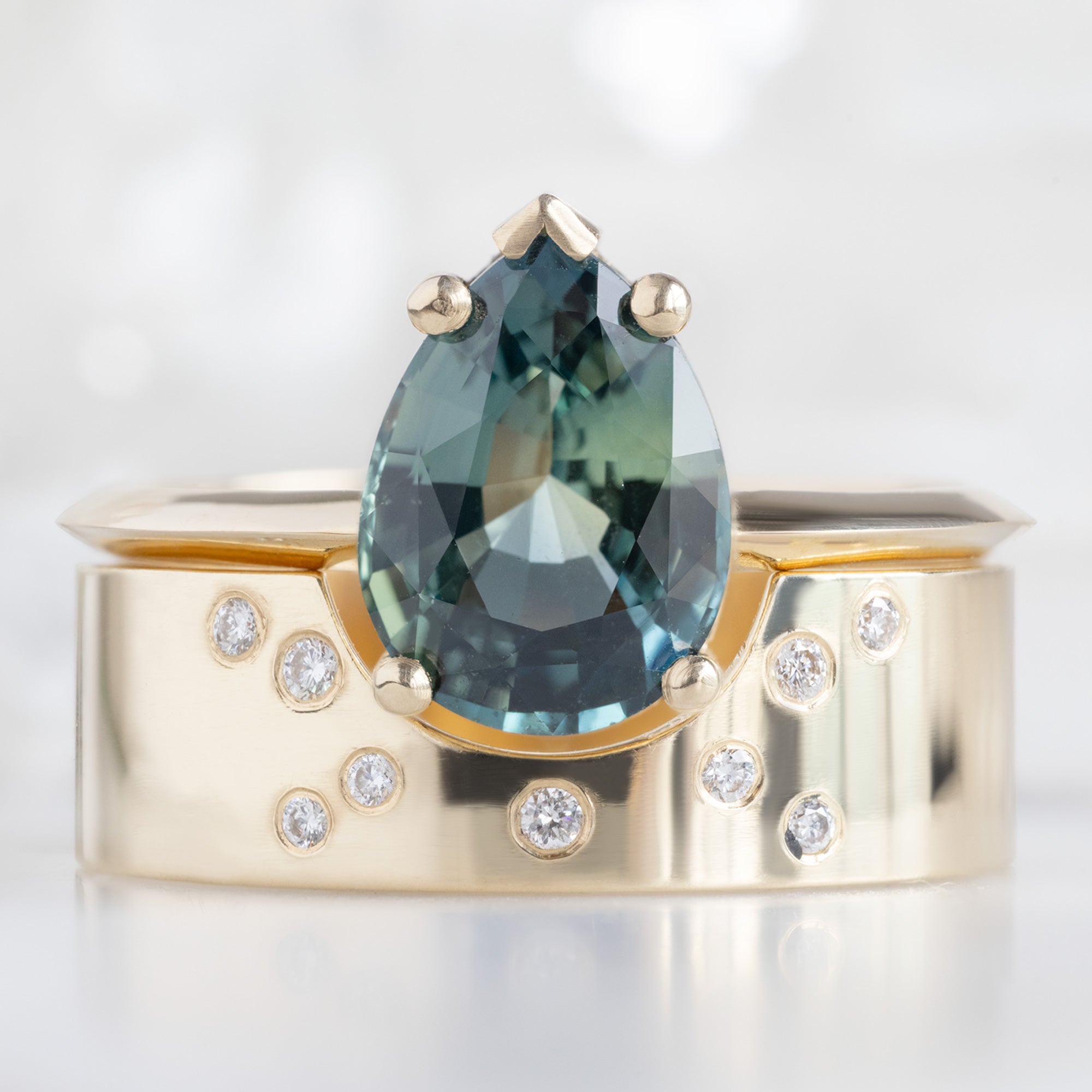 The Sage Ring with a 2.04ct Pear Teal Sapphire in 14 Yellow Gold Stacked with the Constellation Arc Cut Out Stacking Band