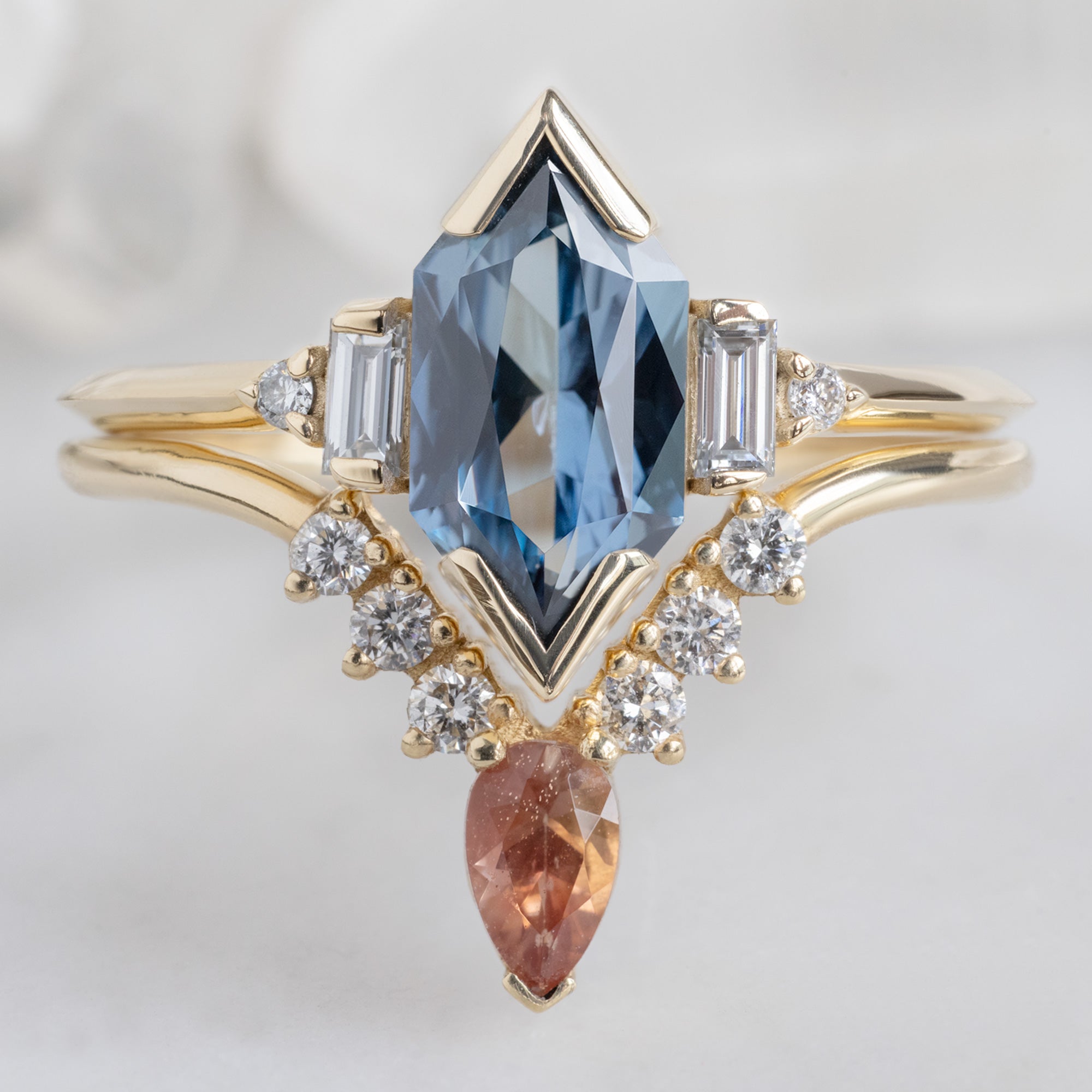 The Primrose Ring with a 1.54ct Blue Sapphire Hexagon in 14K Yellow Gold Stacked with the Sunstone and White Diamond Sunburst Stacking Ring