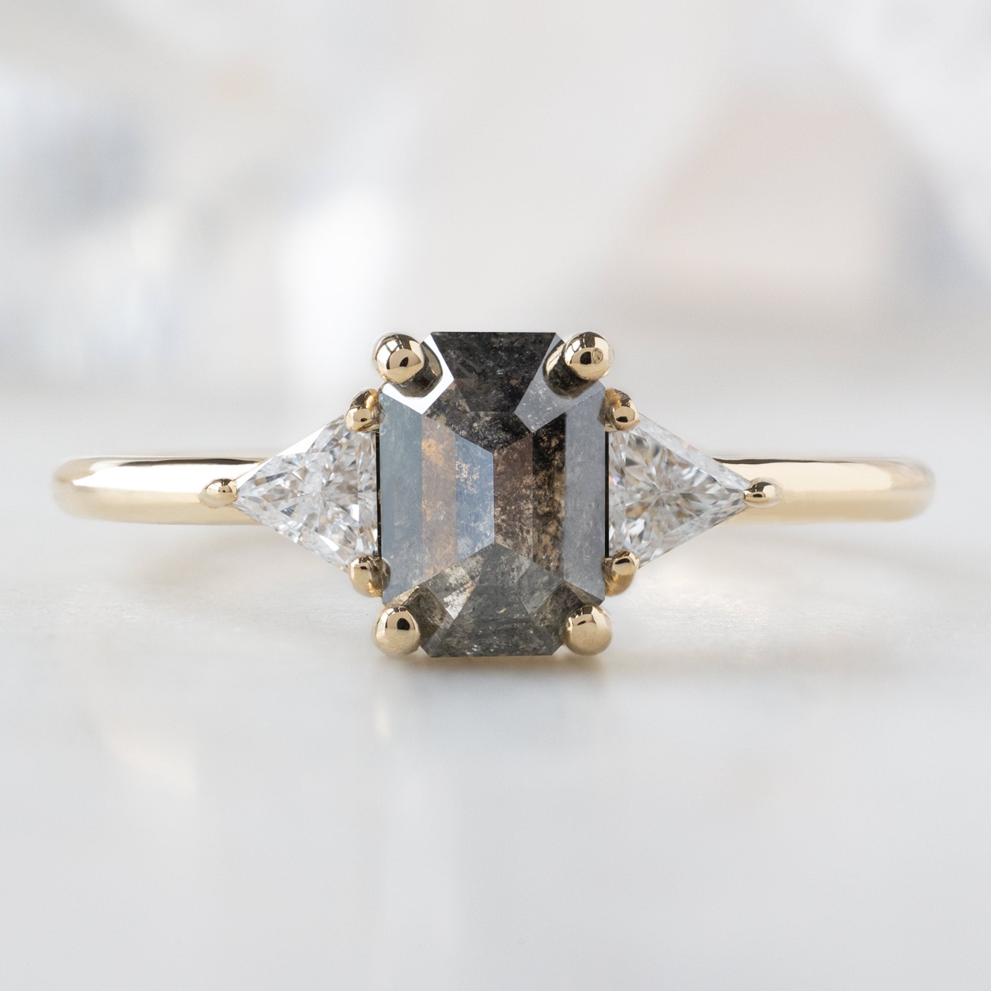 The Jade Ring with a 0.88ct Emerald Cut Salt and Pepper Diamond in 14K Yellow Gold on White Marble