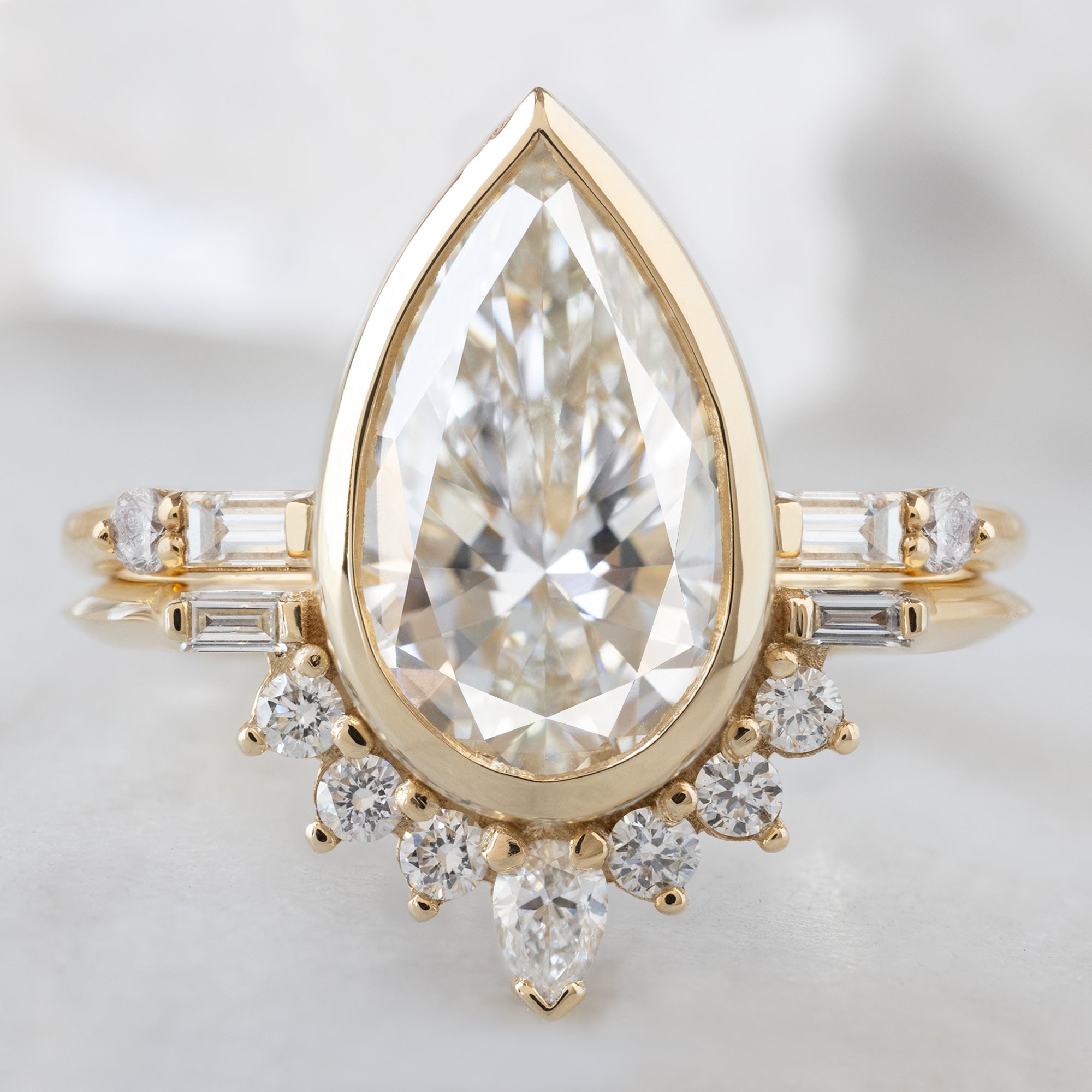 The Posy Ring with a2 .81ct Pear Lab Grown White Diamond in 14K Yellow Gold Stacked with the Lux Open Cuff Baguette Stacking Band on White Marble