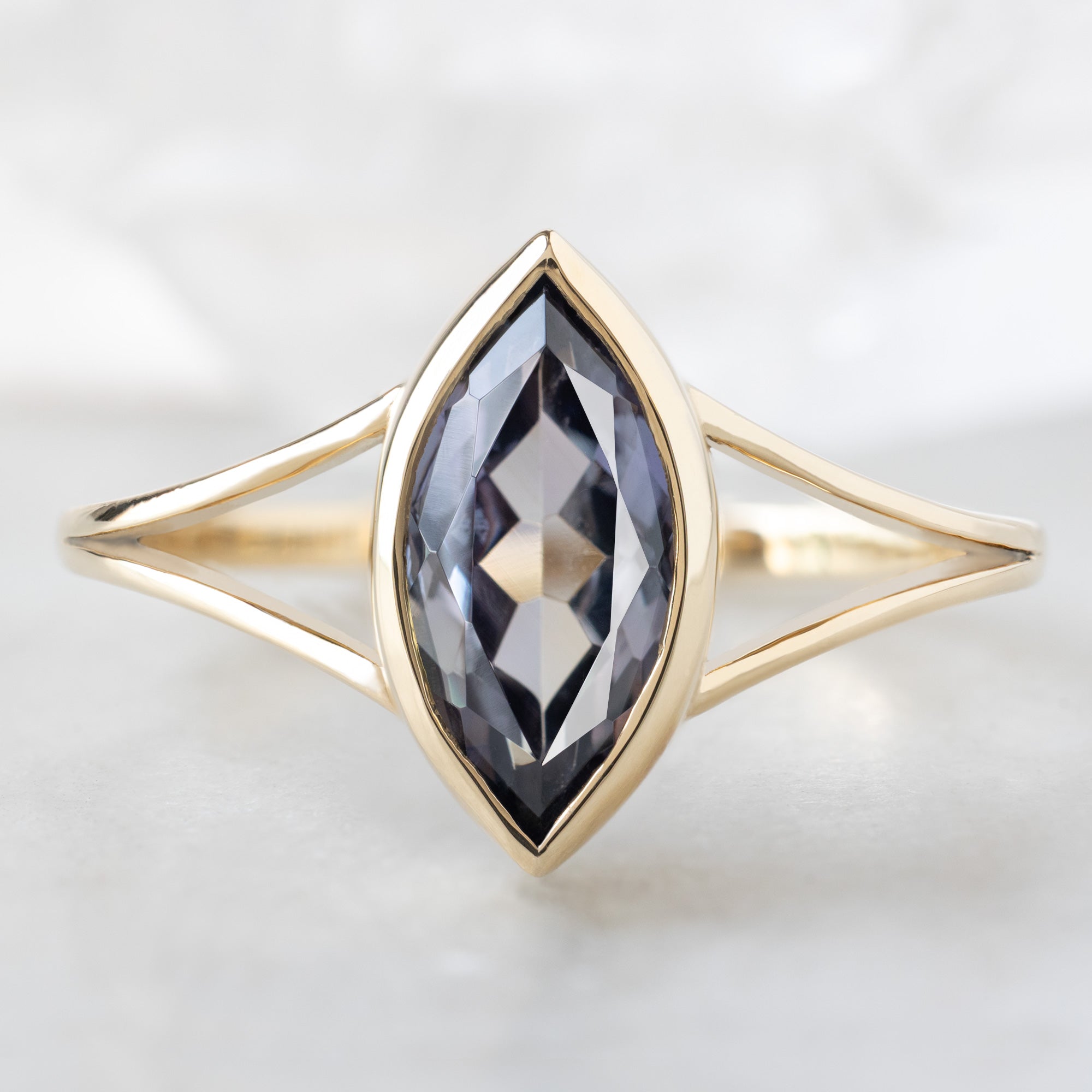 The Magnolia Ring with a 1.63ct Marquise Tanzanite in 14K Yellow Gold on White Marble Tile