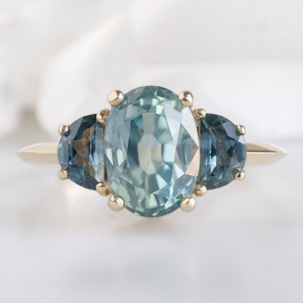 The 3 Stone Ring with a 2.42ct Oval Sapphire in 14K Yellow Gold on White Marble