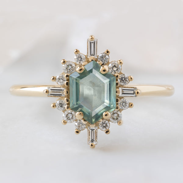 The Compass Ring with a 0.77ct Hexagon Montana Sapphire in 14K Yellow Gold on White Marble Tile