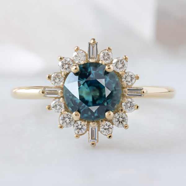 The Compass Ring with a 1.19ct Round Blue Sapphire in 14K Yellow Gold on White Marble