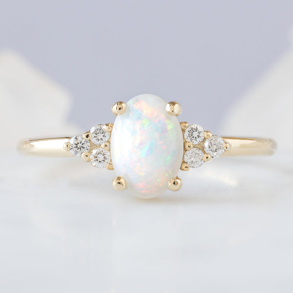 The Ivy Ring with a 0.44ct Oval Australian Opal in 14K Yellow Gold on Pale Blue Background