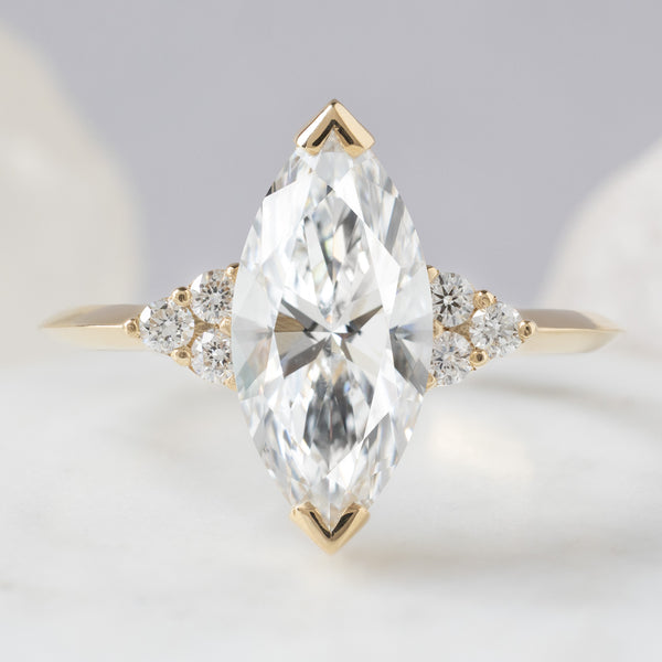 The Ivy Ring with a 1.64ct Marquise Lab Grown White Diamond in 14K Yellow Gold on Light Blue Grey Background
