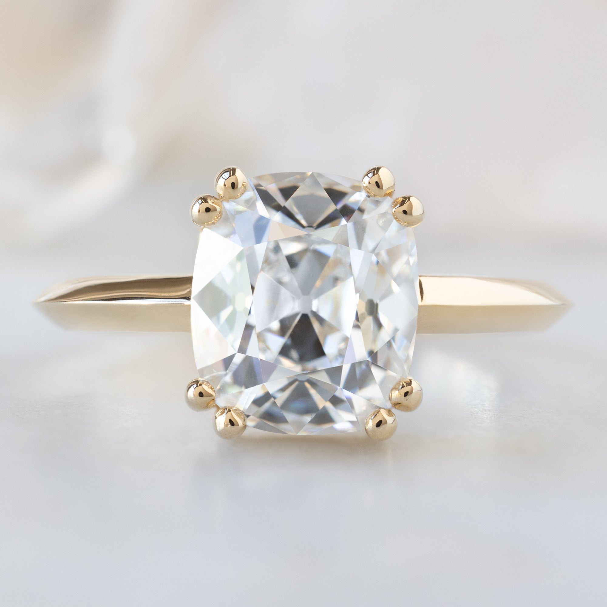 The Bryn Ring with a 2.32ct Old Mine Cut White Diamond in 14K Yellow Gold on White Marble Surface