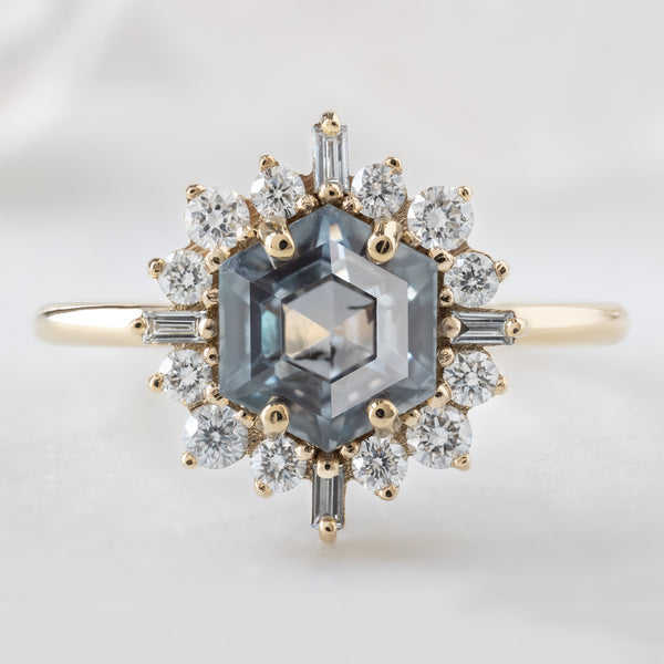 The Compass Ring with a 1.67ct Hexagon Grey Sapphire in 14K Yellow Gold on White Marble Surface
