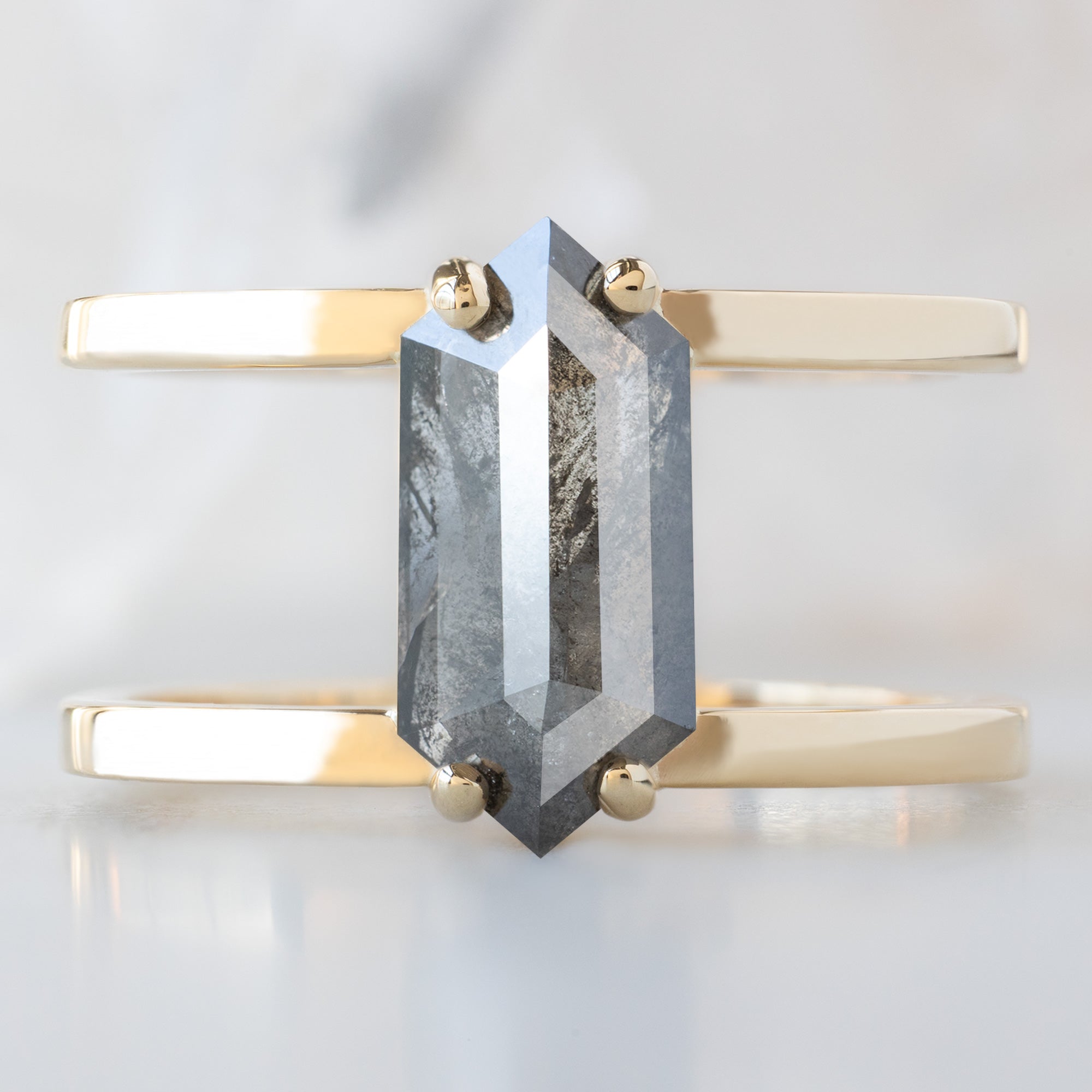 The Poppy Ring with a 1.57ct Hexagon Salt and Pepper Diamond in 14K Yellow Gold on White Marble Surface