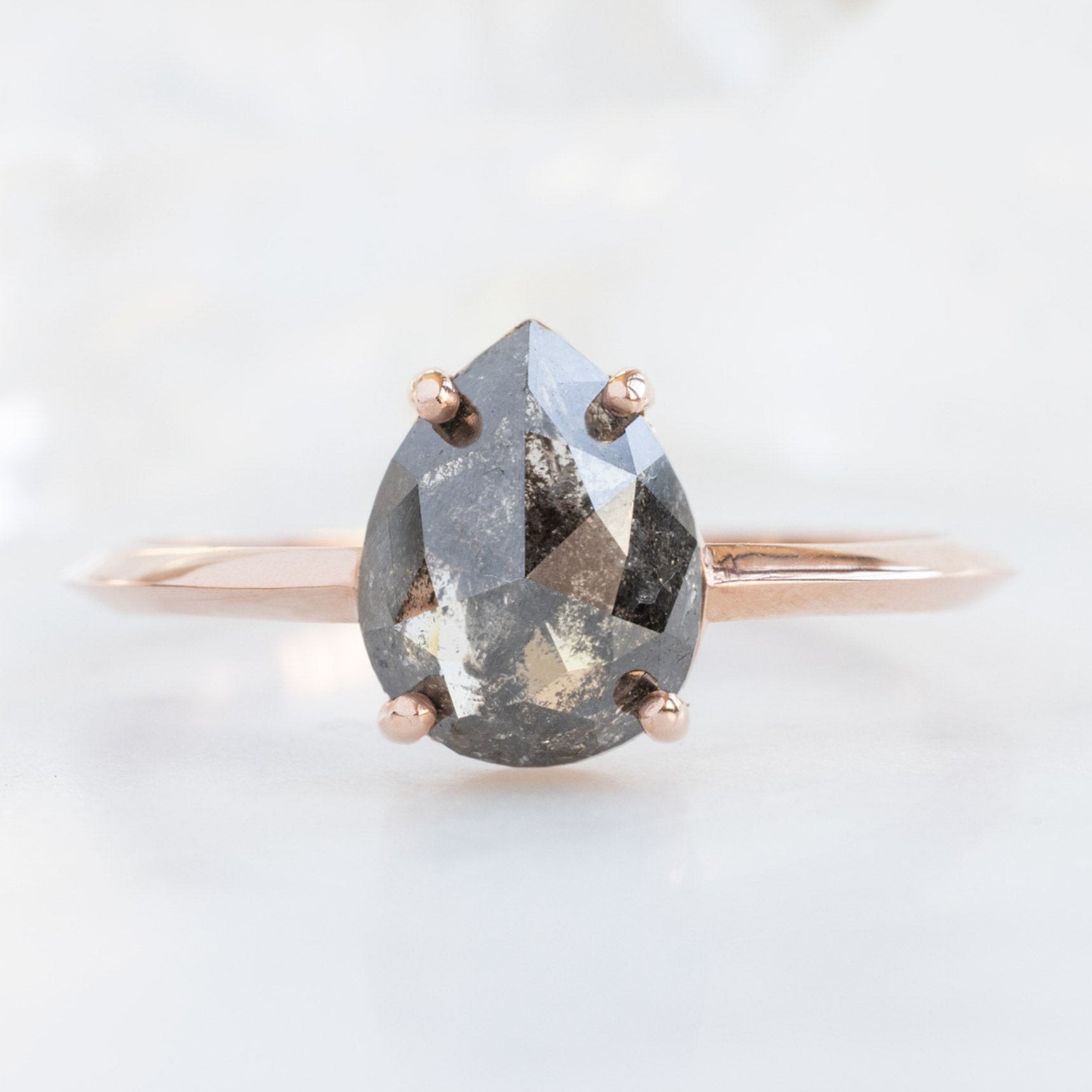 The Bryn Ring with a 1.38ct Pear Black Diamond in 14K Rose Gold on White Marble