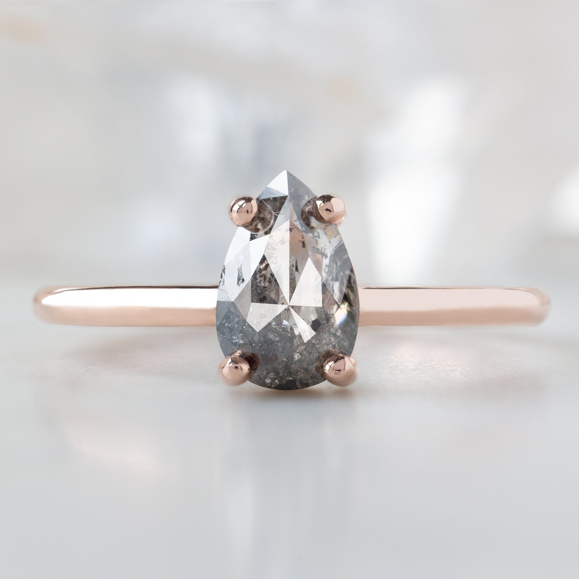 The Bryn Ring with a 0.90ct Pear Salt and Pepper Diamond in 14K Rose Gold on White Marble