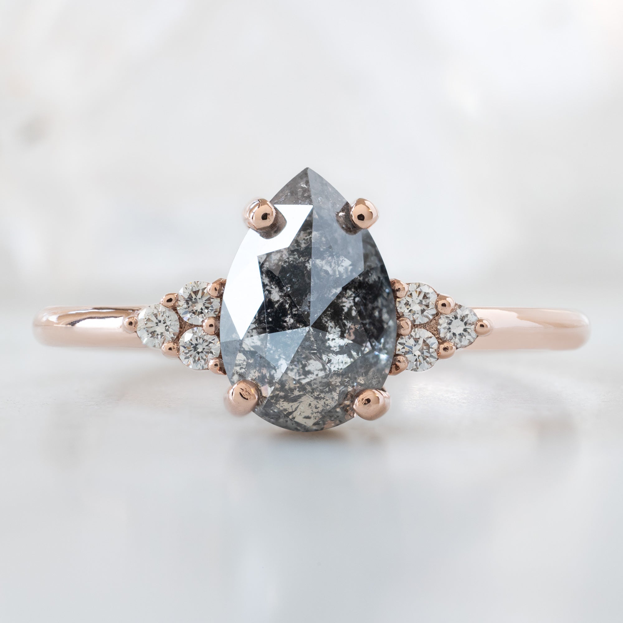 The Ivy Ring with a 1.54ct Pear Salt and Pepper Diamond in 14K Rose Gold on White Marble