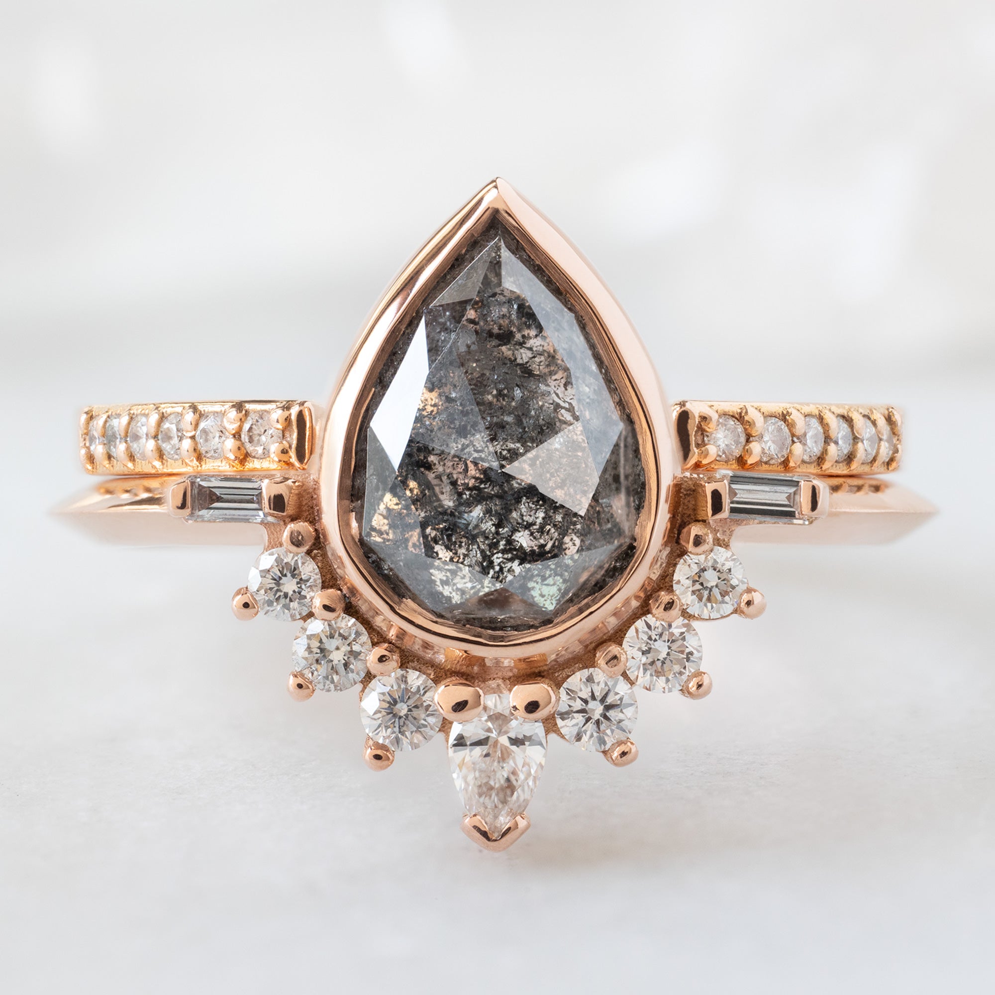 The Posy Ring with a 1.32ct Pear Black Diamond in 14K Rose Gold Stacked with the Open Cuff White Pavé Diamond Stacking Band on White Marble Surface