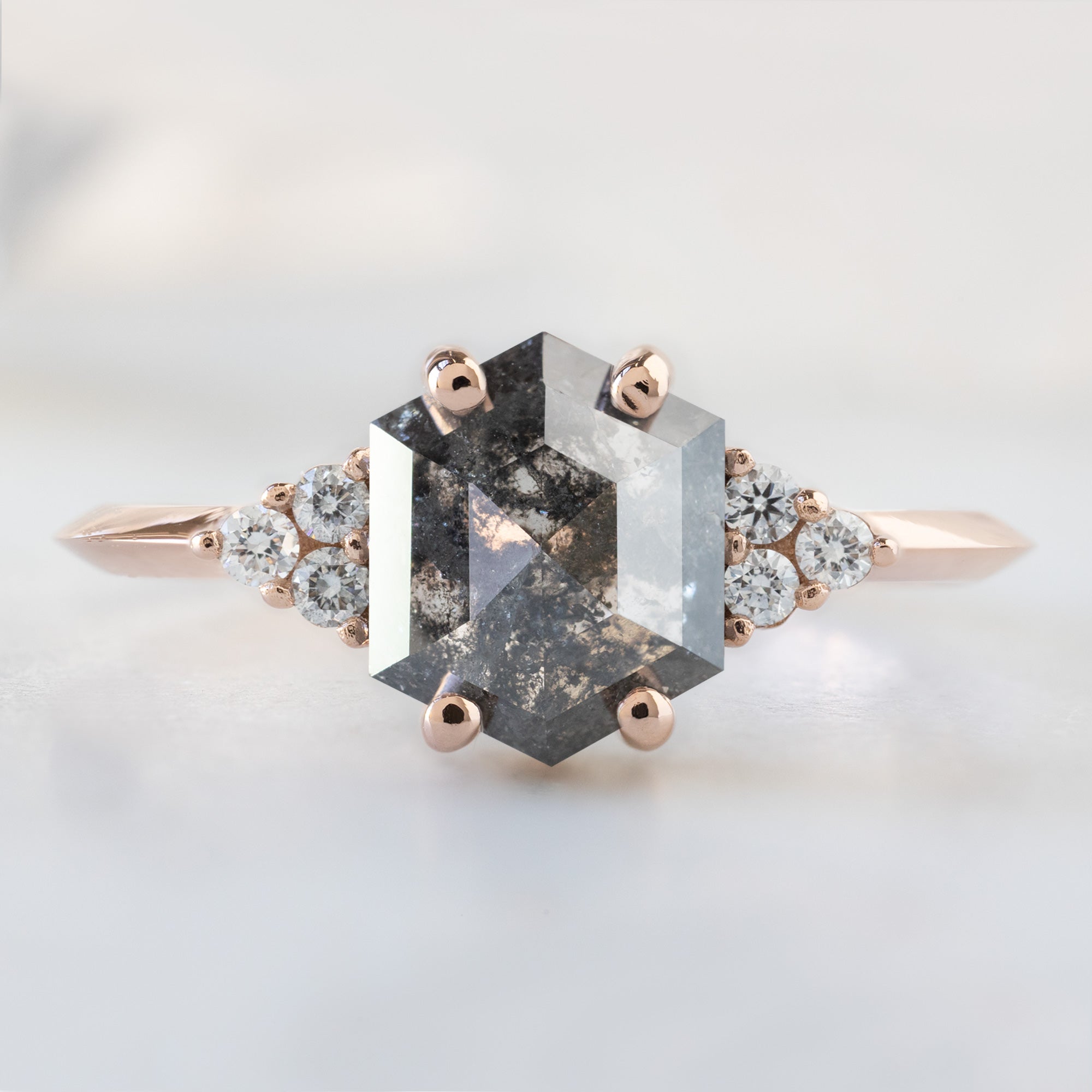 The Ivy Ring with a 1.53ct Hexagon Salt and Pepper Diamond in 14K Rose Gold on White Marble Surface