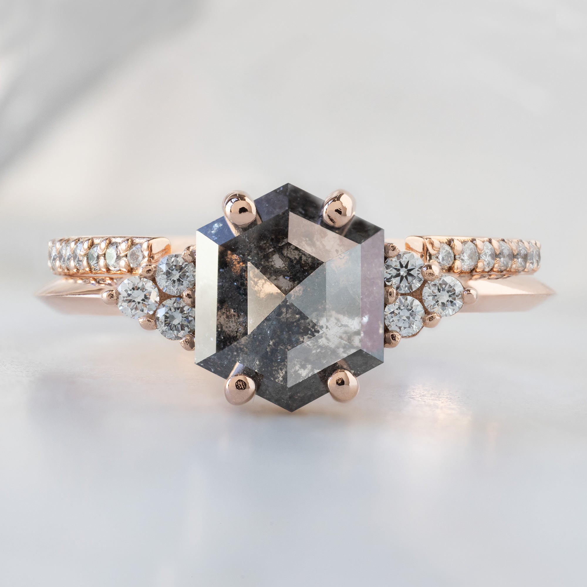 The Ivy Ring with a 1.53ct Hexagon Salt and Pepper Diamond in 14K Rose Gold Stacked with the Open Cuff White Diamond Pavé Stacking Band on White Marble Surface