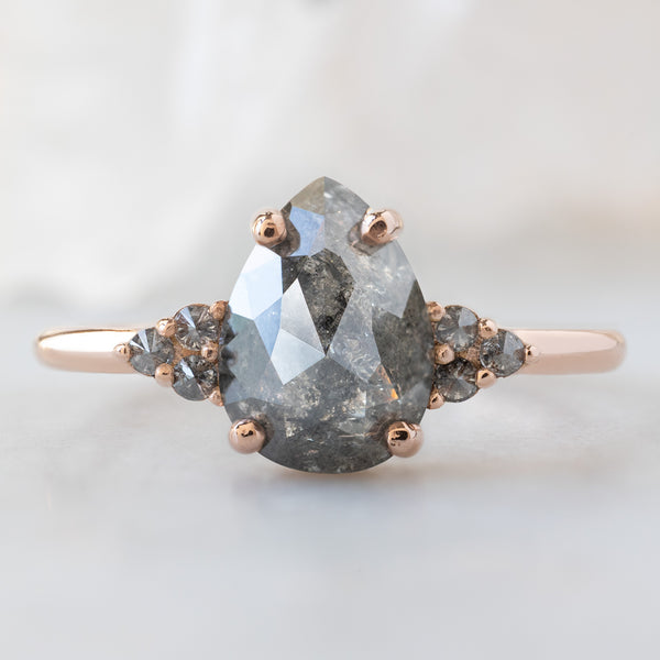 The Ivy Ring with a 1.43ct Pear Salt and Pepper Diamond in 14K Rose Gold on White Marble Surface