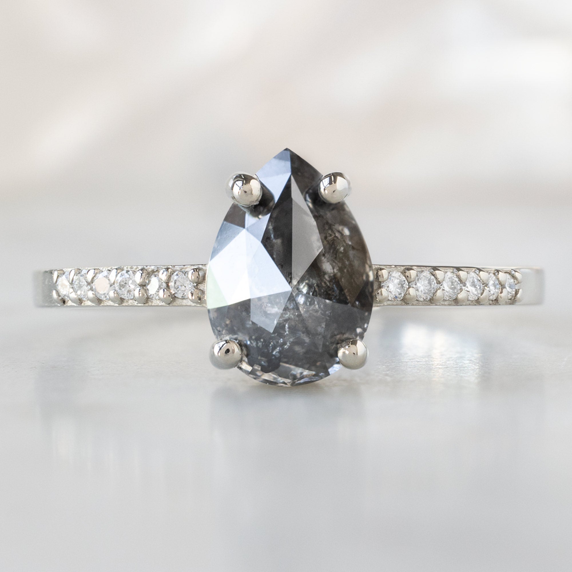 The Willow Ring with a 1.32ct Pear Black Diamond in 14K White Gold on White Marble