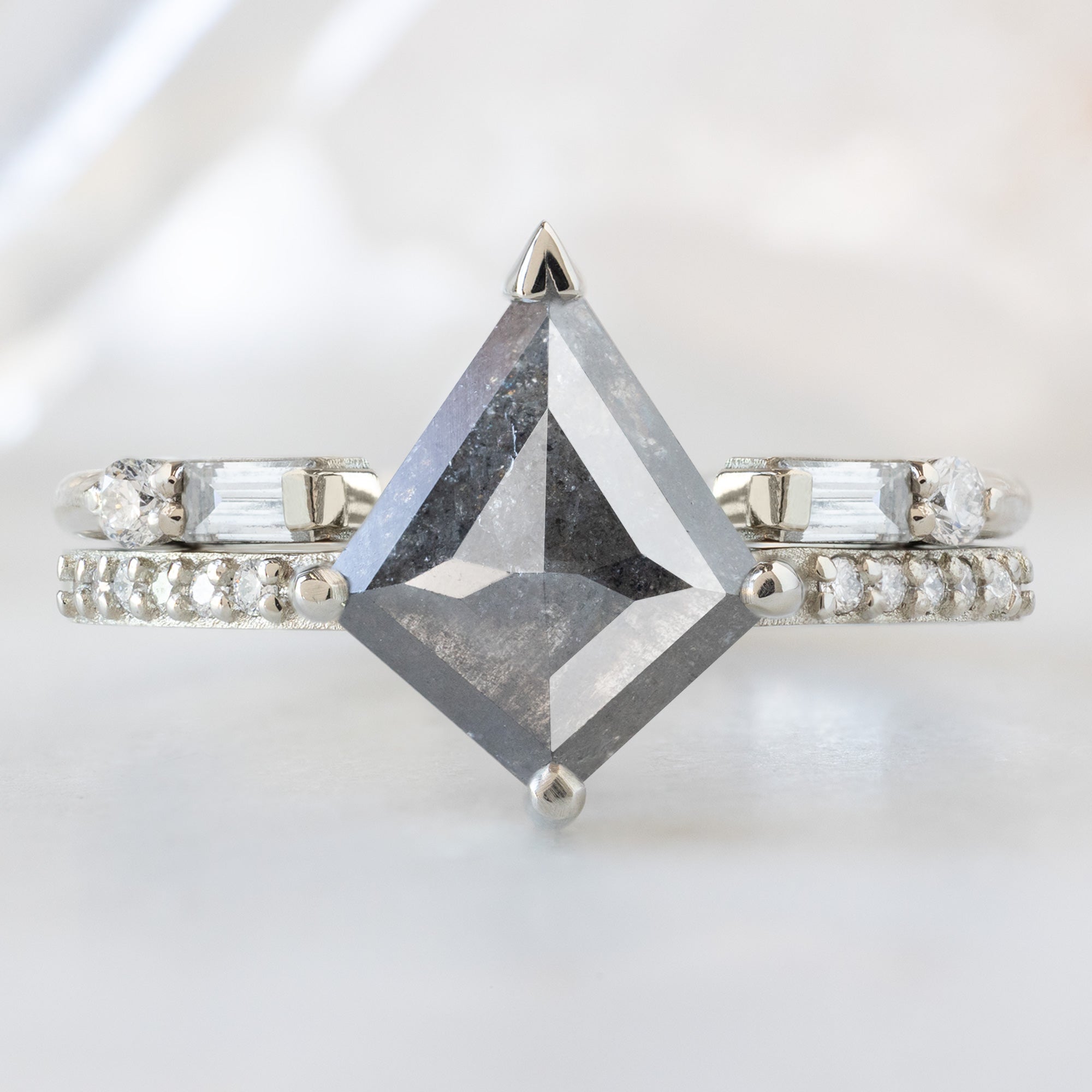 The Willow Ring with a 1.46 Kite Salt and Pepper Diamond in White Gold Stacked with the Luxe Open Cuff White Diamond Baguette Stacking Band on White Marble Surface