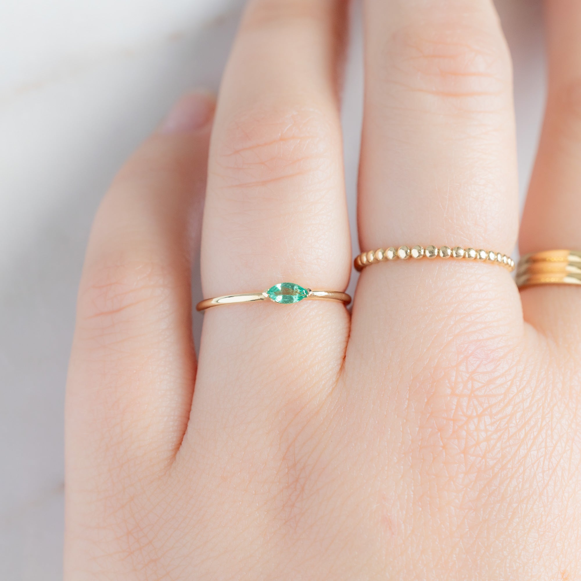 The Teensy Emerald Ring in 14k Yellow Gold stacked on model