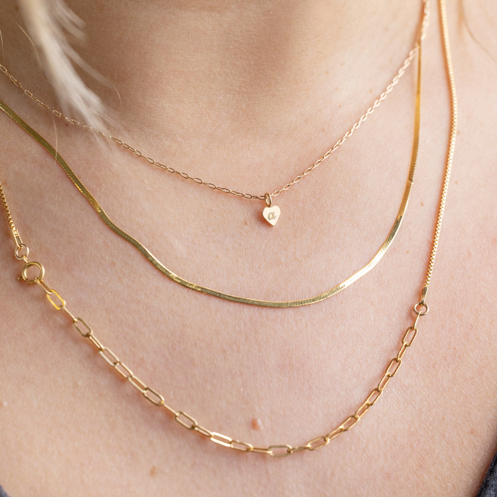 The Heart Pendant Necklace with an engraved 'A' in Yellow Gold Layered on Model