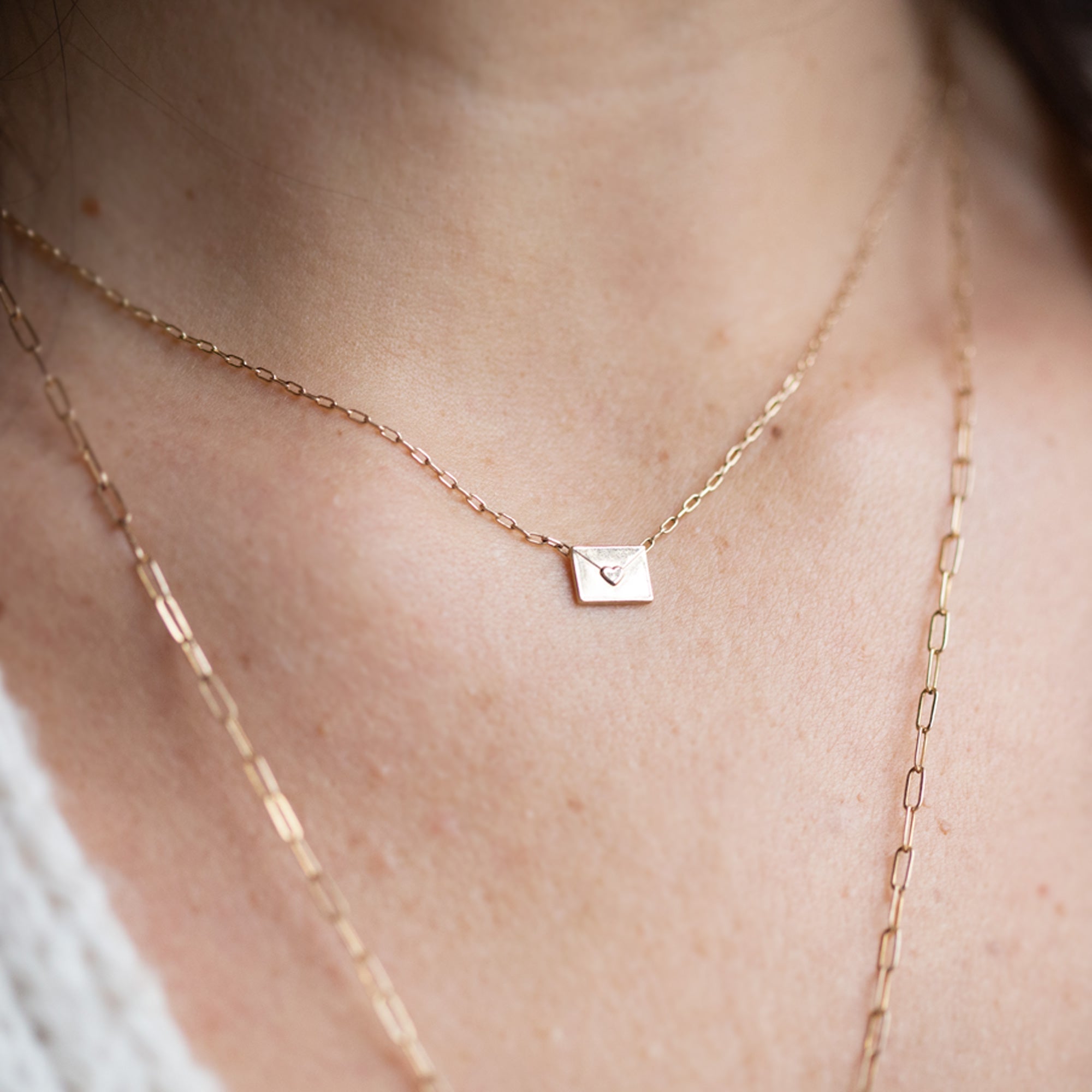 Yellow Gold necklace featuring a loveletter shaped pendant on model