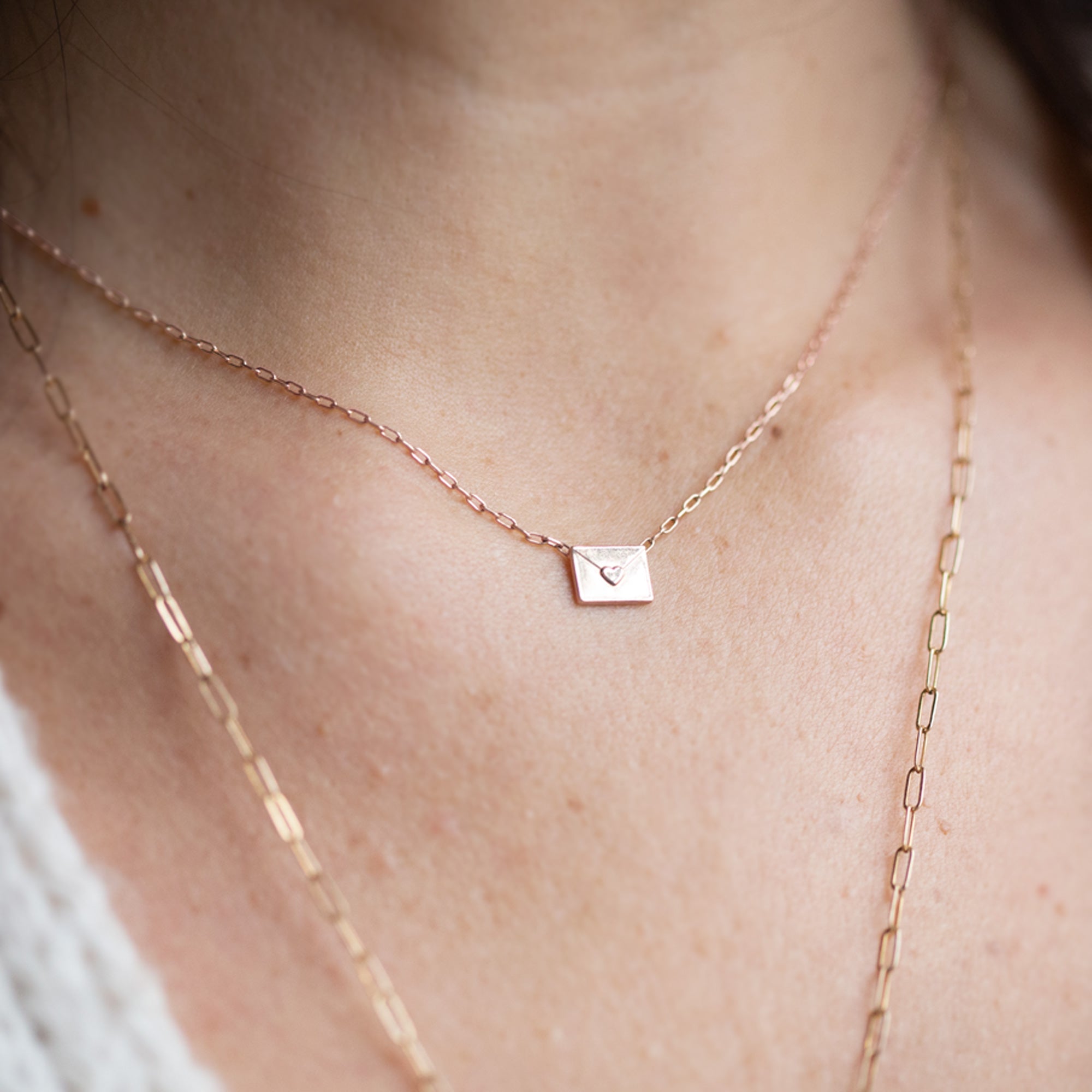 rose gold necklace featuring a loveletter shaped pendant on model